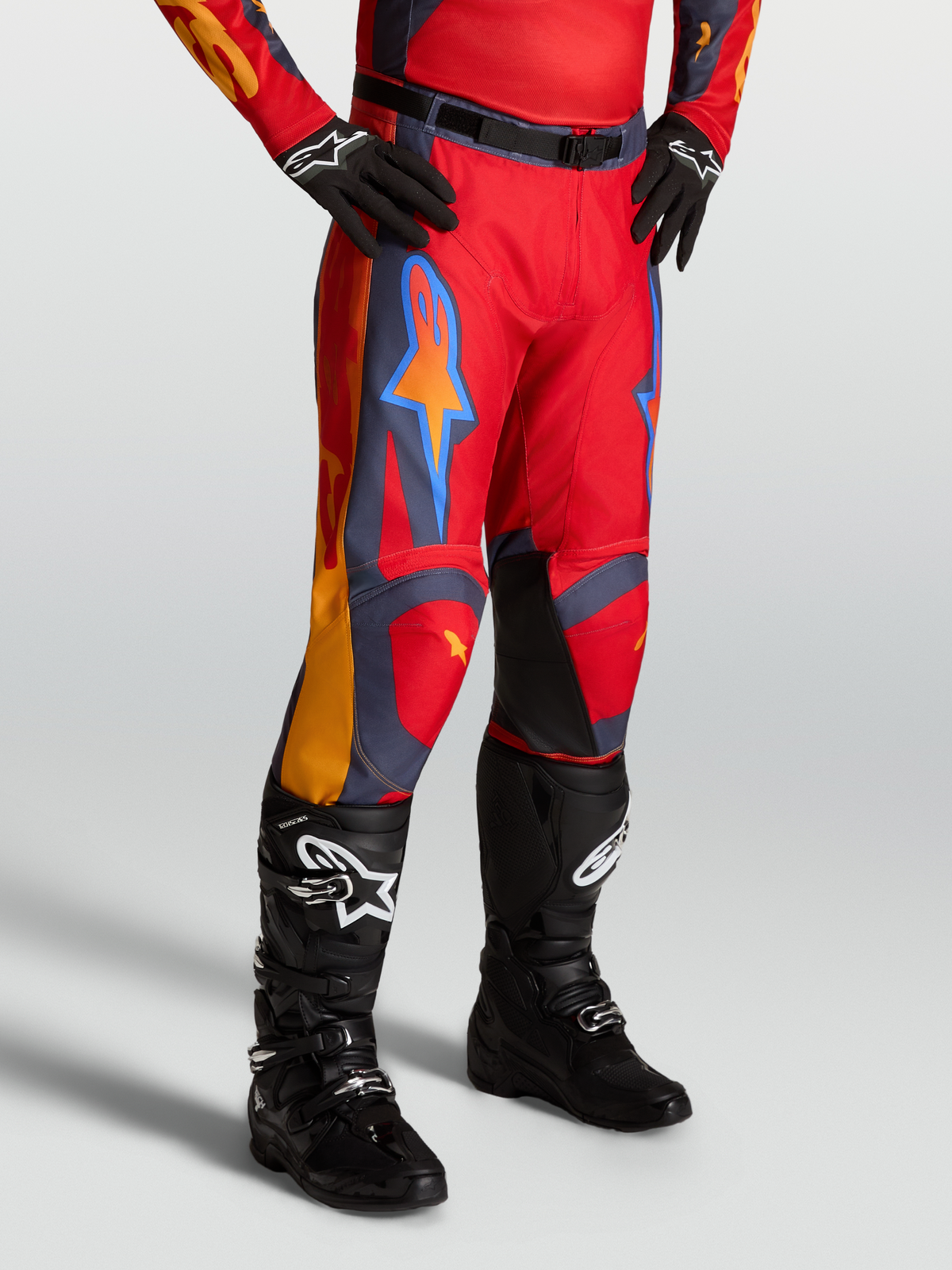 Alpinestars Racer Hunt, pantalones de motocross para hombre, rojos con detalles en gris y coral, usados con botas negras