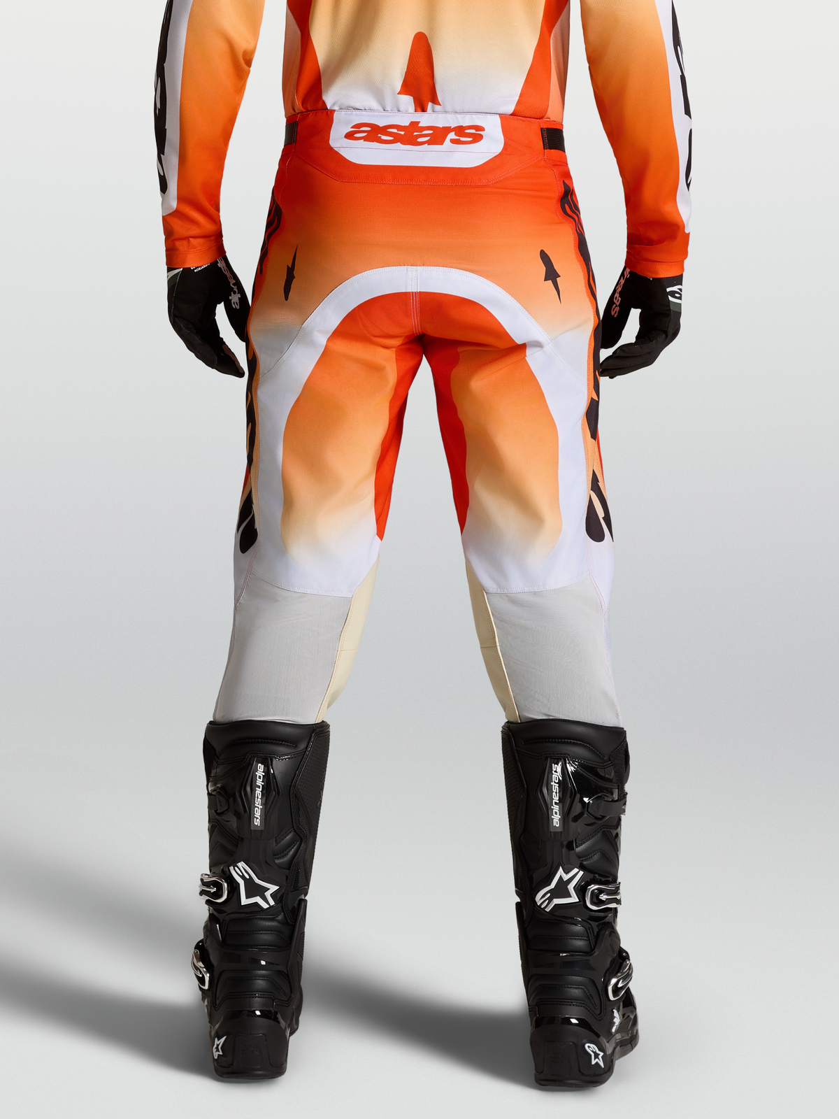 Alpinestars Pantalones Racer Amber, pantalones de motocross para hombre, rojos y blancos, vista trasera con botas negras, diseño off-road técnico