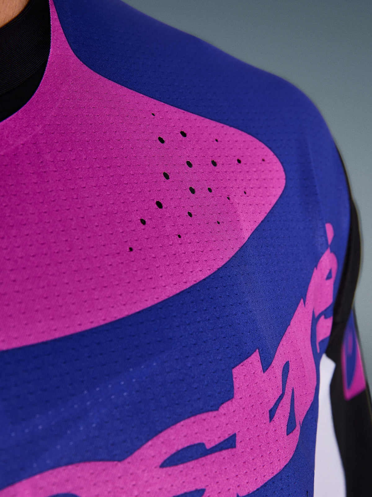 Jersey Alpinestars Techstar Knif 2026, jersey de motocross, negro, gris claro y púrpura, primer plano del pecho con perforaciones cortadas con láser y tejido elástico que absorbe la humedad para una mayor ventilación