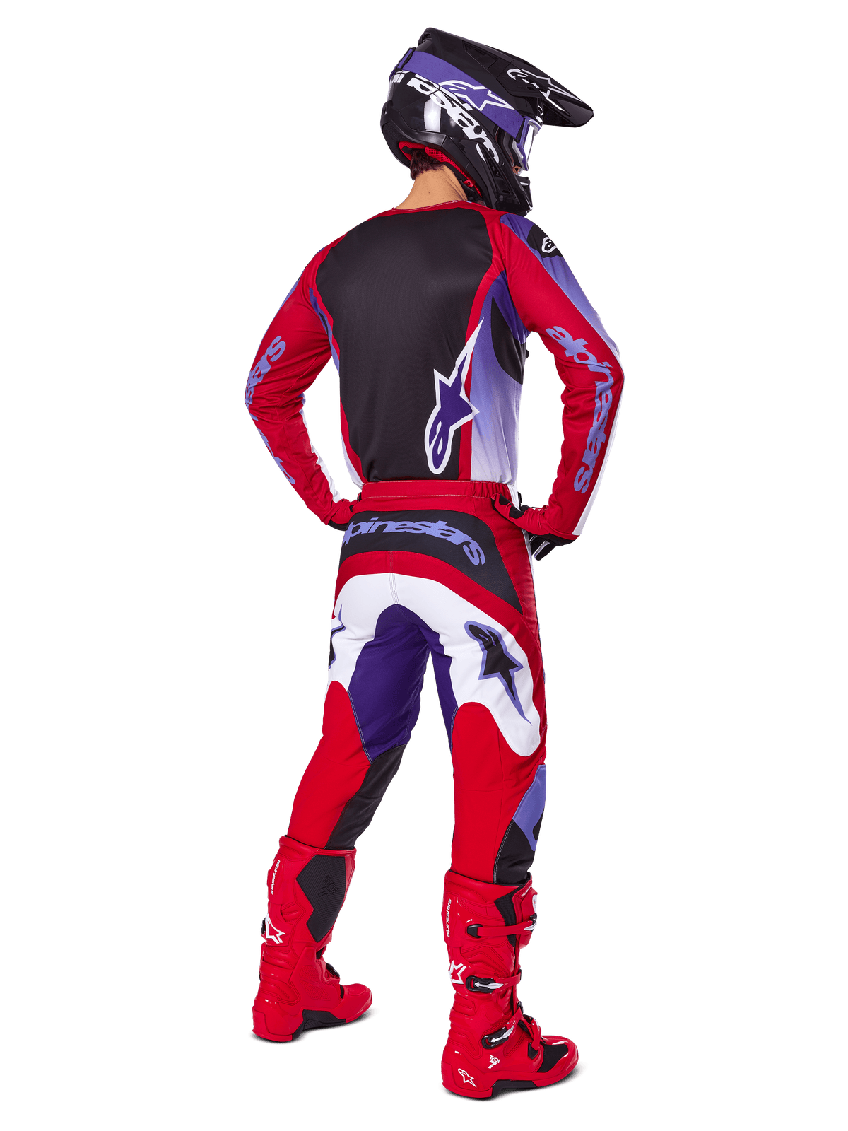 Piloto de motocross visto desde atrás con el conjunto Alpinestars 2025 Fluid Wurx, jersey morado y rojo brillante con panel trasero negro, pantalones de motocross a juego con detalles en blanco y morado, botas rojo brillante y casco negro, equipamiento profesional de carreras todoterreno