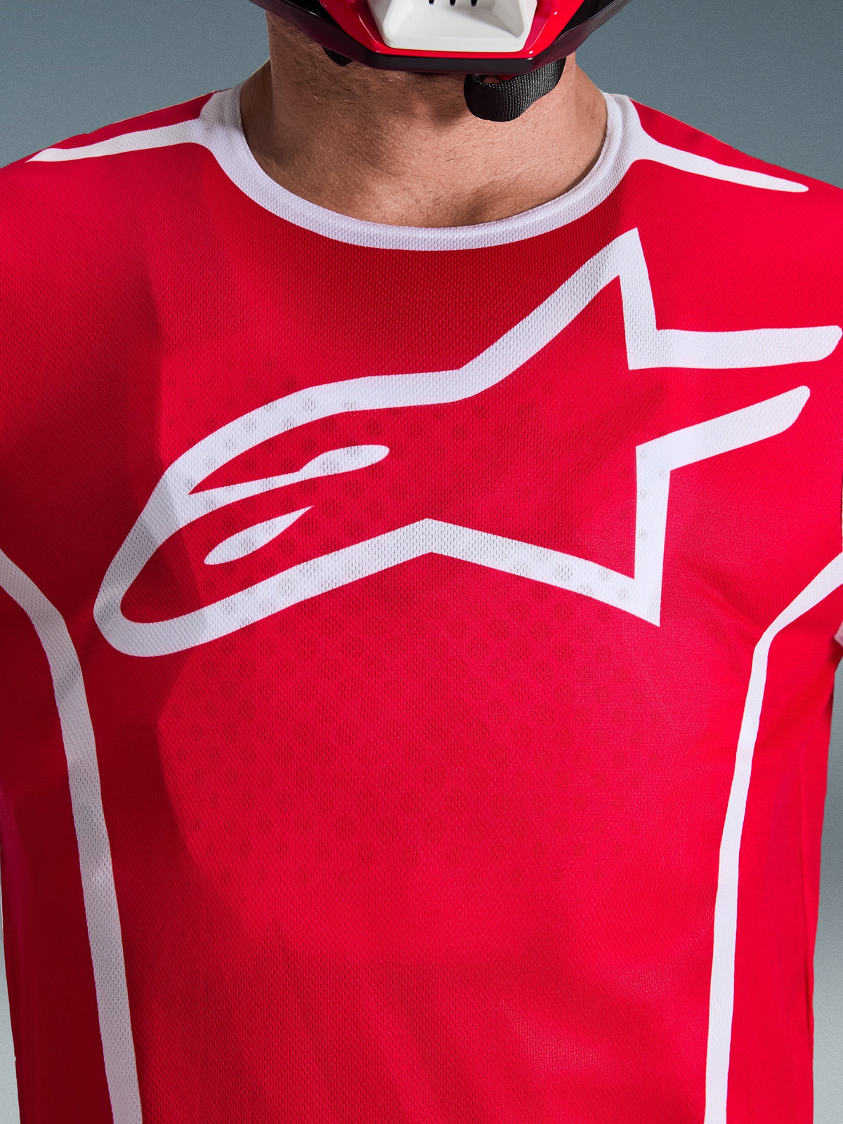 Alpinestars 2026 Fluid Apex Jersey, rojo y blanco, vista de cerca del pecho con el logotipo de Astars en blanco, cuello deportivo blanco y tejido transpirable para rendimiento en motocross