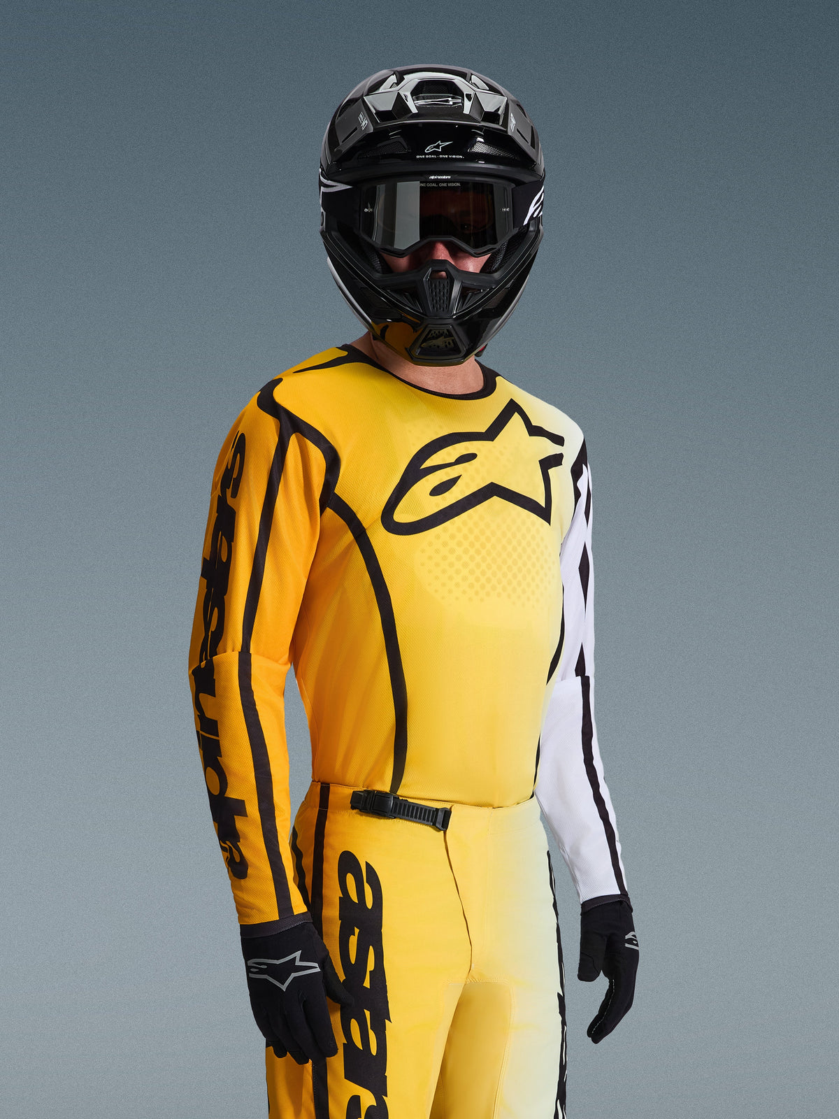 Alpinestars 2026 Fluid Apex Jersey, jersey de motocross, amarillo y negro con acentos blancos, usado por un piloto con casco y gafas negras, gran logotipo de estrella negra en el pecho, conjunto de equipamiento de carreras todoterreno coordinado