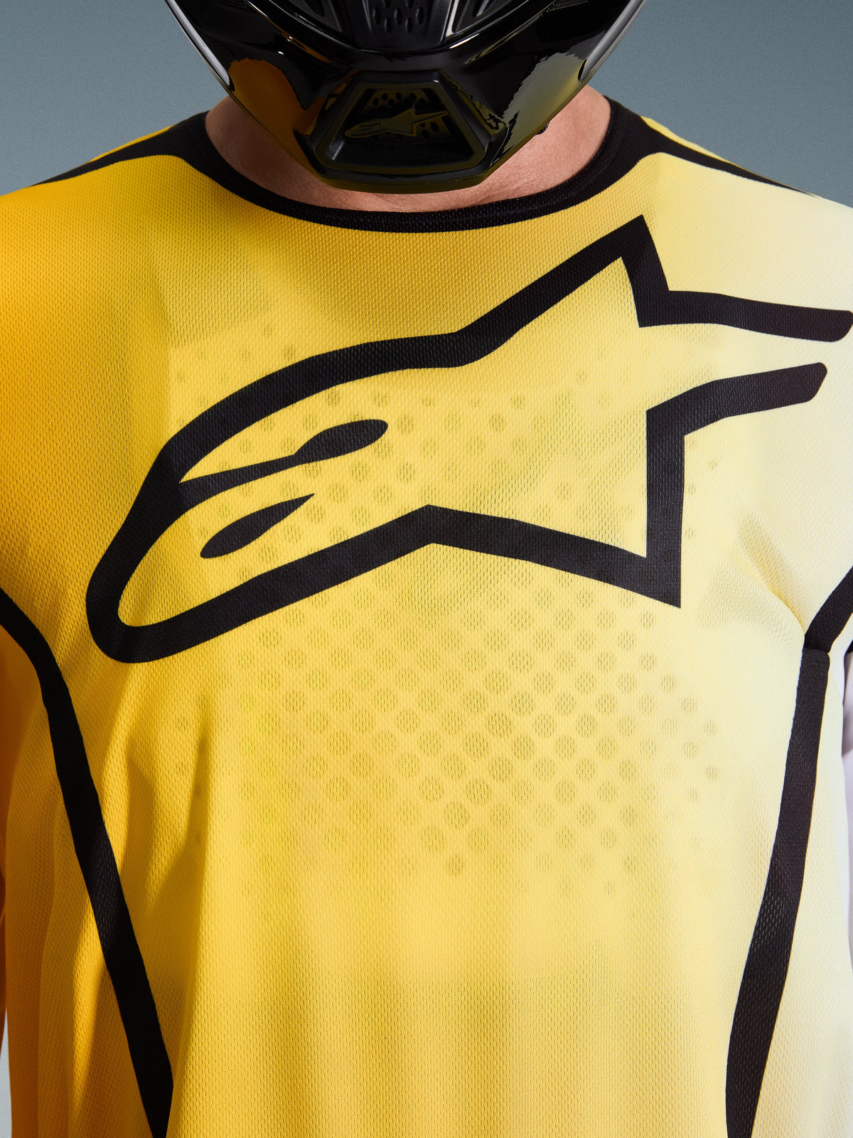 Alpinestars 2026 Fluid Apex Jersey, jersey de motocross, amarillo brillante y negro, vista de cerca con un gran logotipo Astar negro en el pecho, tejido de poliéster transpirable que absorbe la humedad y cuello deportivo