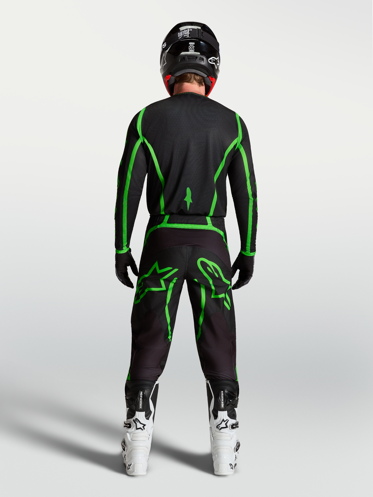 Alpinestars Fluid Apex V2 Pants, Black and Green Fluo motocross gear shown from behind on a rider with white boots.