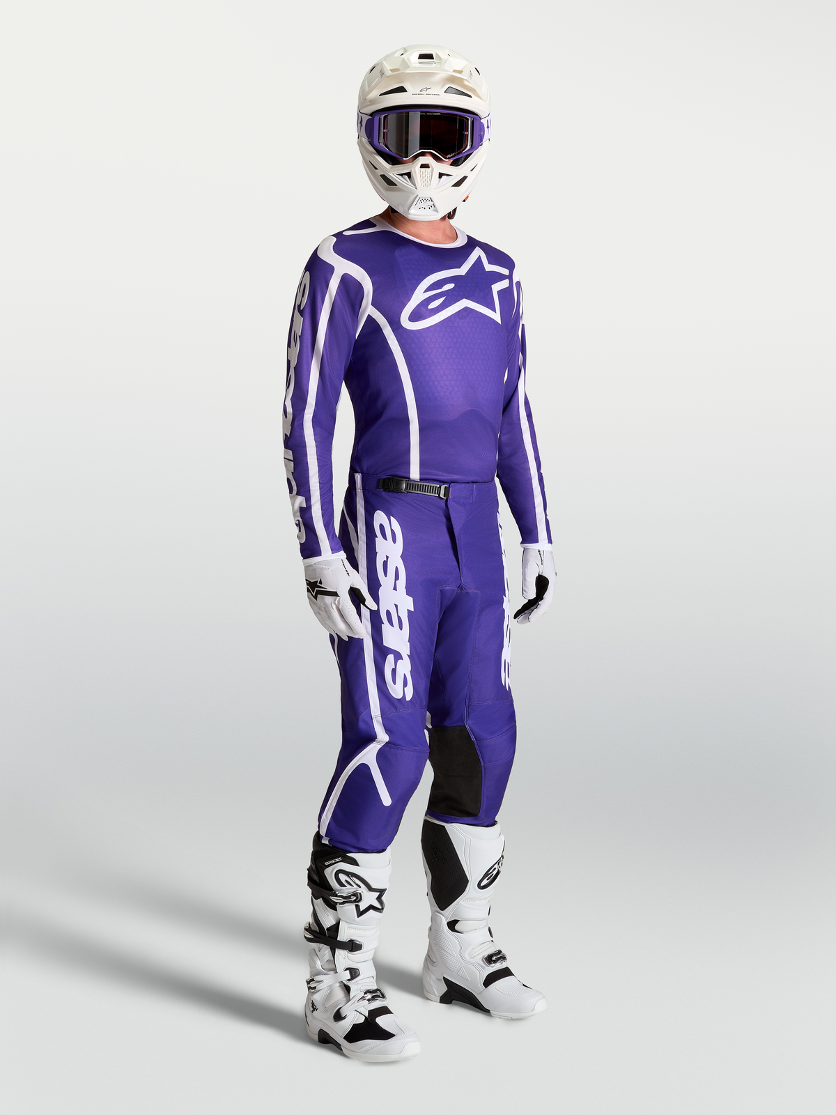 Jersey Alpinestars Fluid Apex V2 y pantalones a juego, conjunto de motocross para hombre en azul profundo y blanco, con casco y botas blancas, equipación técnica para pilotaje off-road