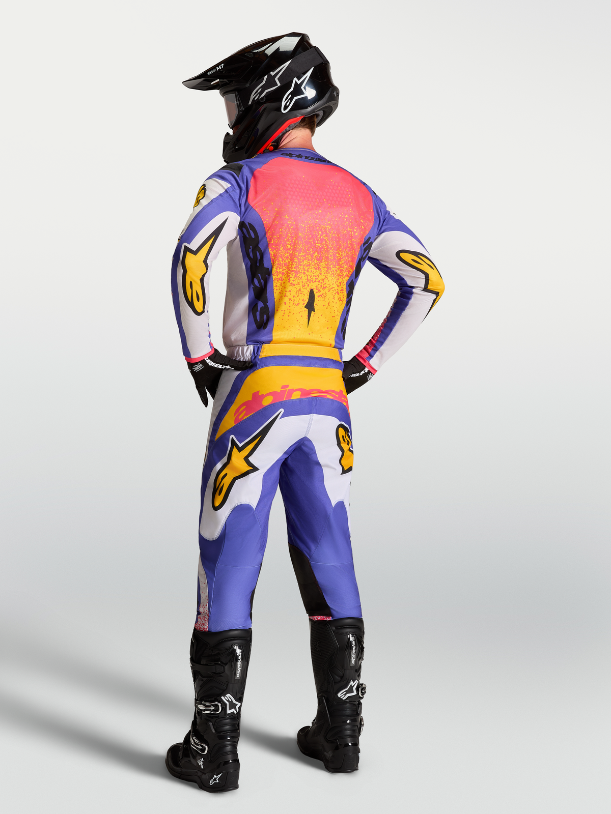 Alpinestars Fluid Drag, conjunto de jersey y pantalones de motocross para hombre, azul y lila claro con detalles dorados, vista trasera en modelo