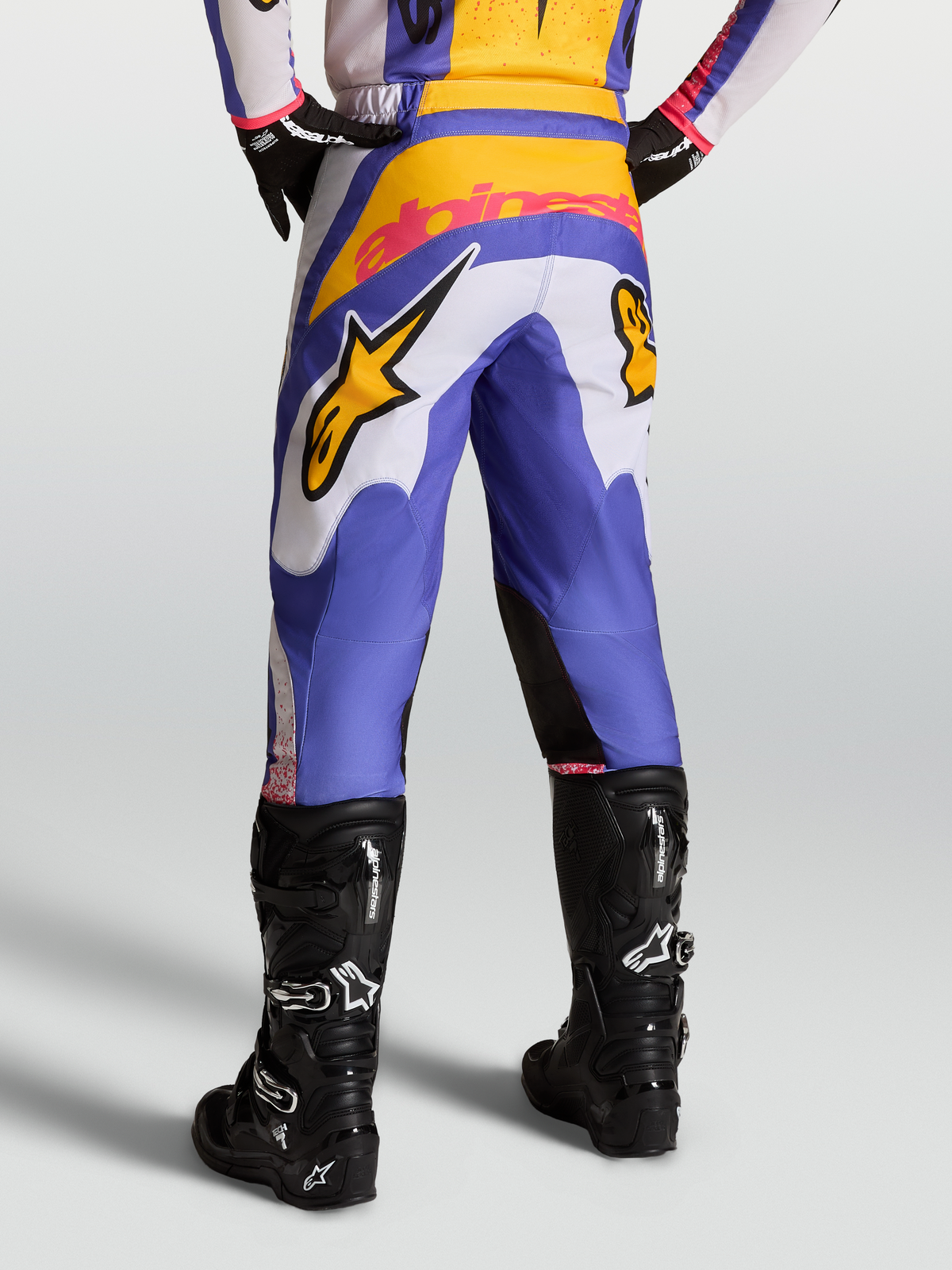 Pantalones Fluid Drag, equipo de motocross para hombre, diseño en azul y dorado con piernas precurvadas y canesú reforzado, usados con botas negras, ideales para off-road.