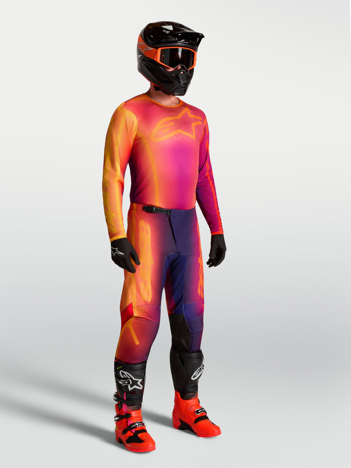 Jersey Alpinestars Fluid Kepler, jersey de motocross morado y naranja en modelo con equipo de carreras a juego.