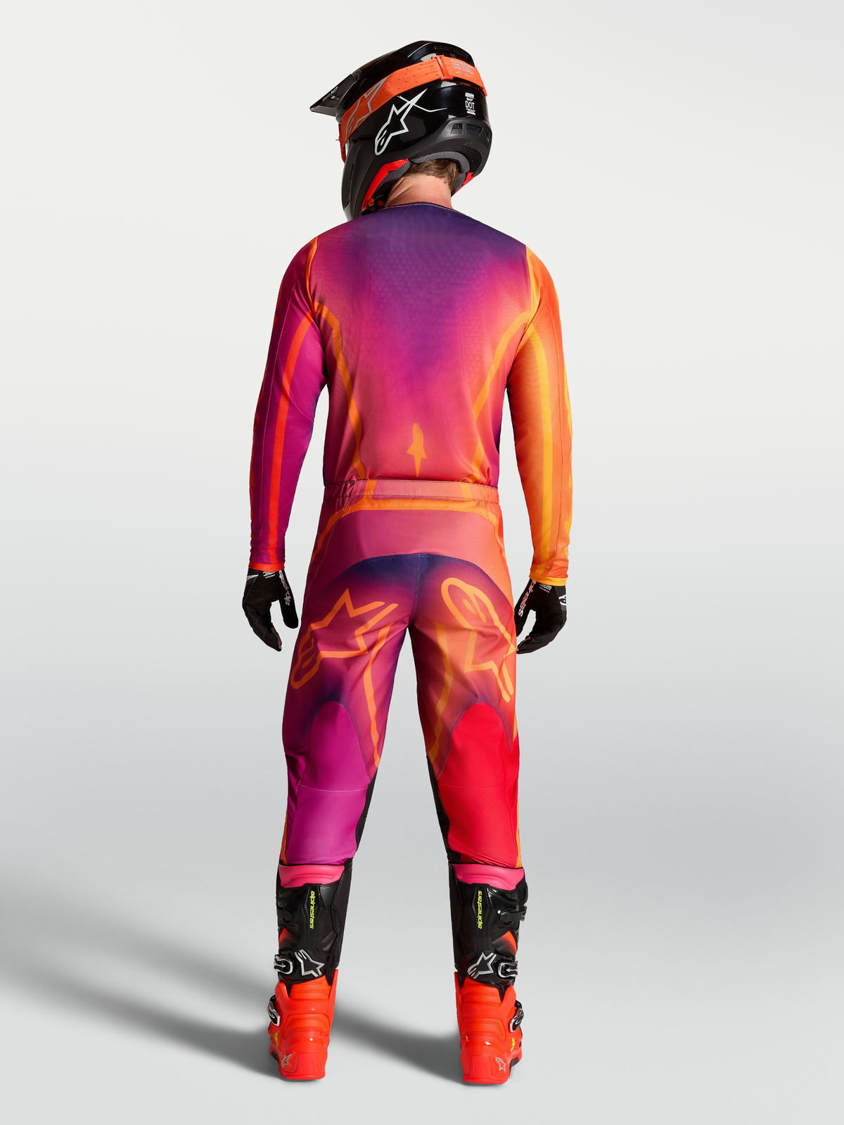Alpinestars Pantalones Fluid Kepler, de motocross morados y naranja, vista posterior con jersey y botas, ajuste deportivo