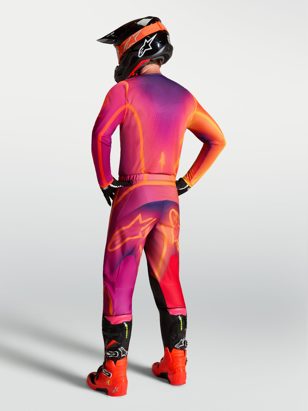 Jersey Alpinestars Fluid Kepler, equipo de motocross morado y naranja visto desde atrás en un piloto.