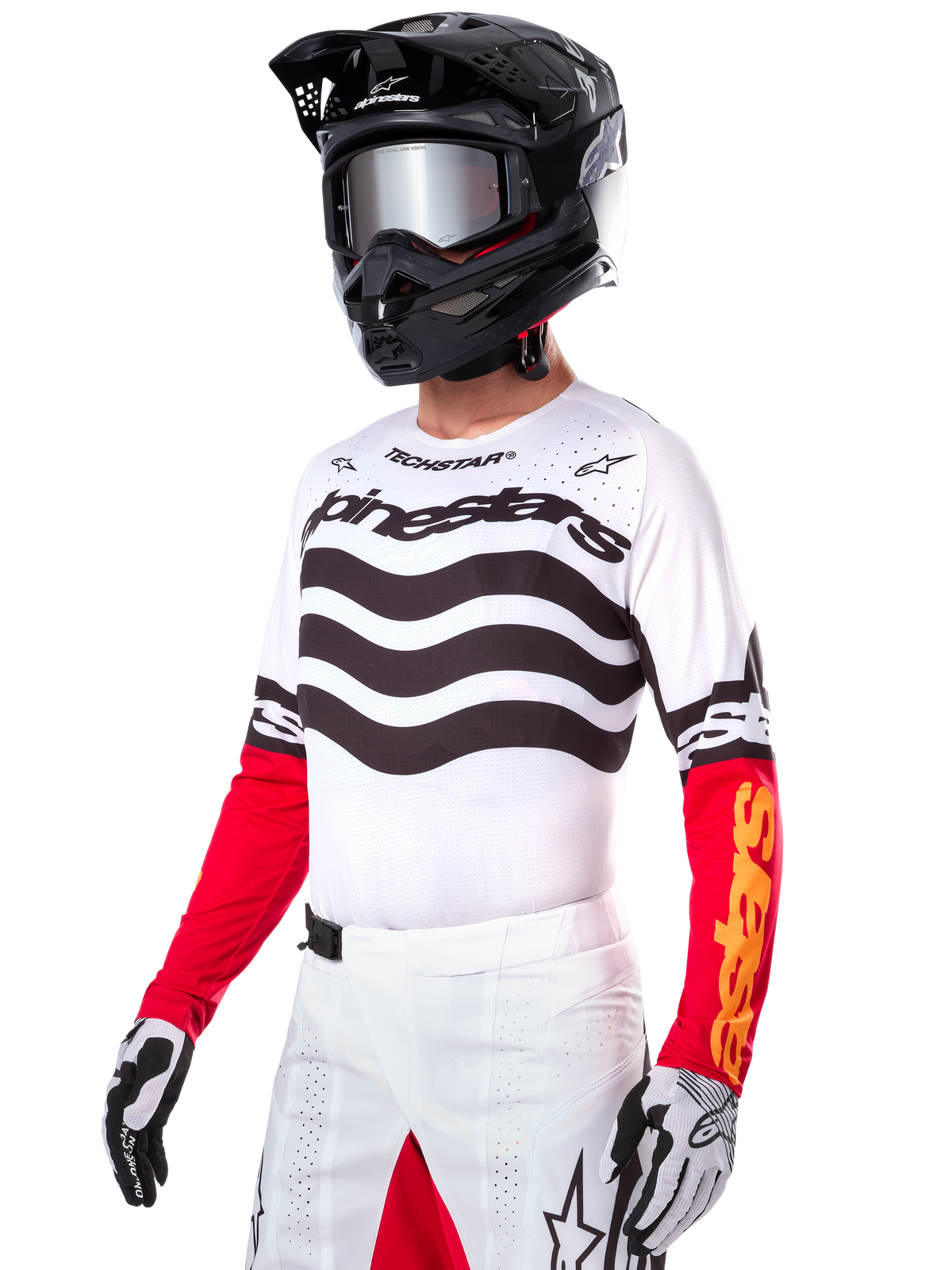 Motocross rider wearing the Alpinestars Limited Edition Techstar Deep Jersey, white jersey featuring black wavy stripes and red lower sleeves, styled with a black helmet, mirrored goggles, white and black gloves, and white racing pants, performance motocross outfit.