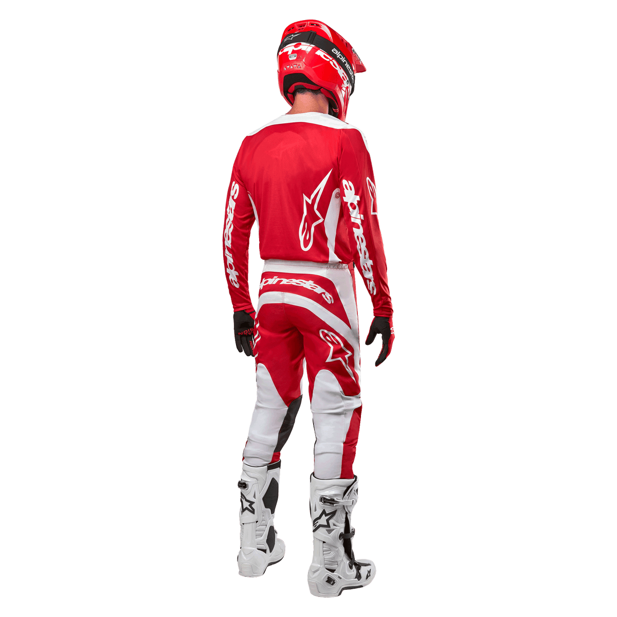 Vista posterior de un piloto de motocross con el Jersey Alpinestars Fluid Lurv 2024 en color rojo y blanco, combinado con pantalones rojos y blancos a juego, botas de motocross blancas y un casco rojo, mostrando el diseño de la espalda y la marca Alpinestars.