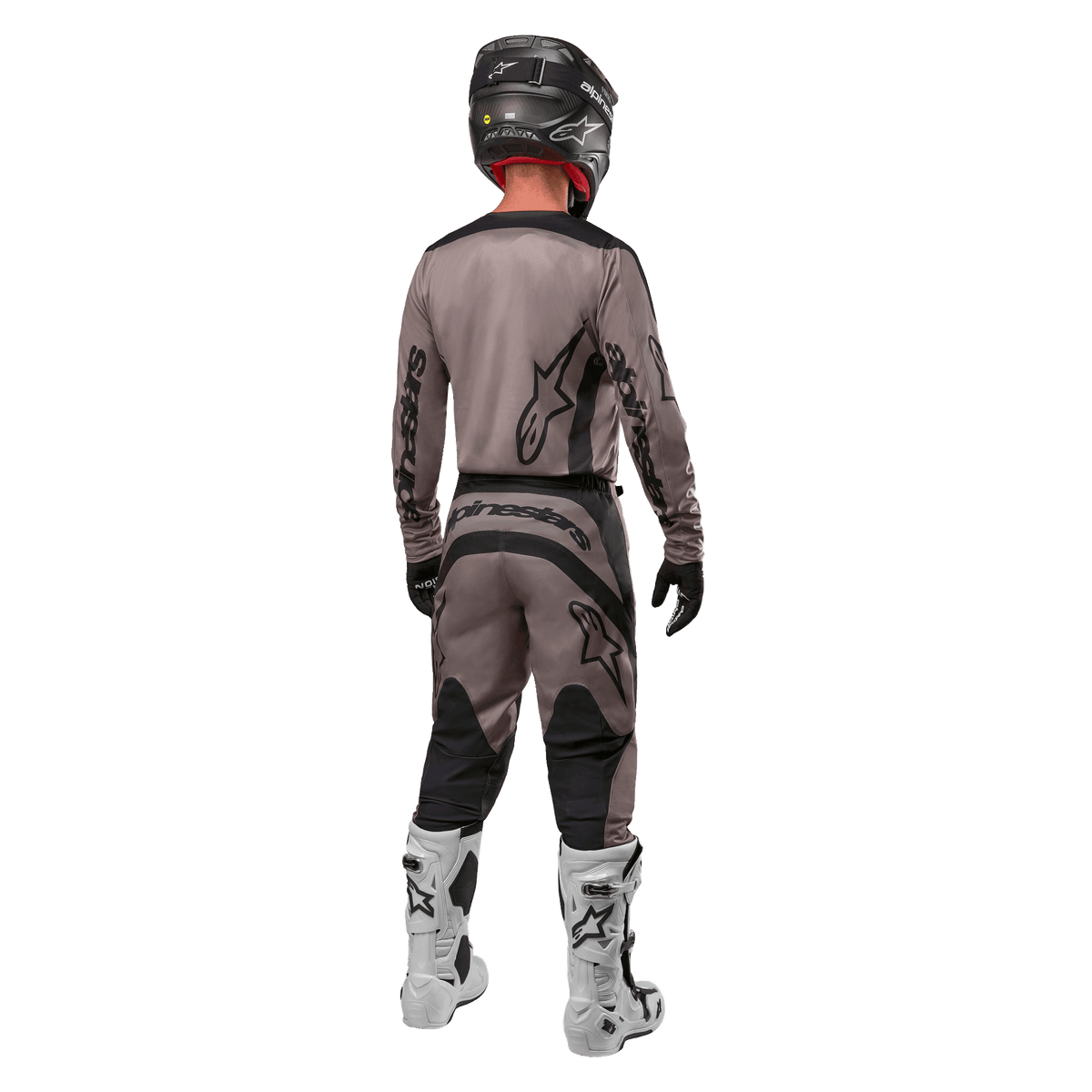 Alpinestars 2024 Fluid Lurv Jersey, jersey de motocross, Mud Black, vista trasera de un piloto de motocross con equipamiento de carreras a juego, casco negro y botas blancas, con logotipos negros de Alpinestars y un ajuste atlético para rendimiento todoterreno.