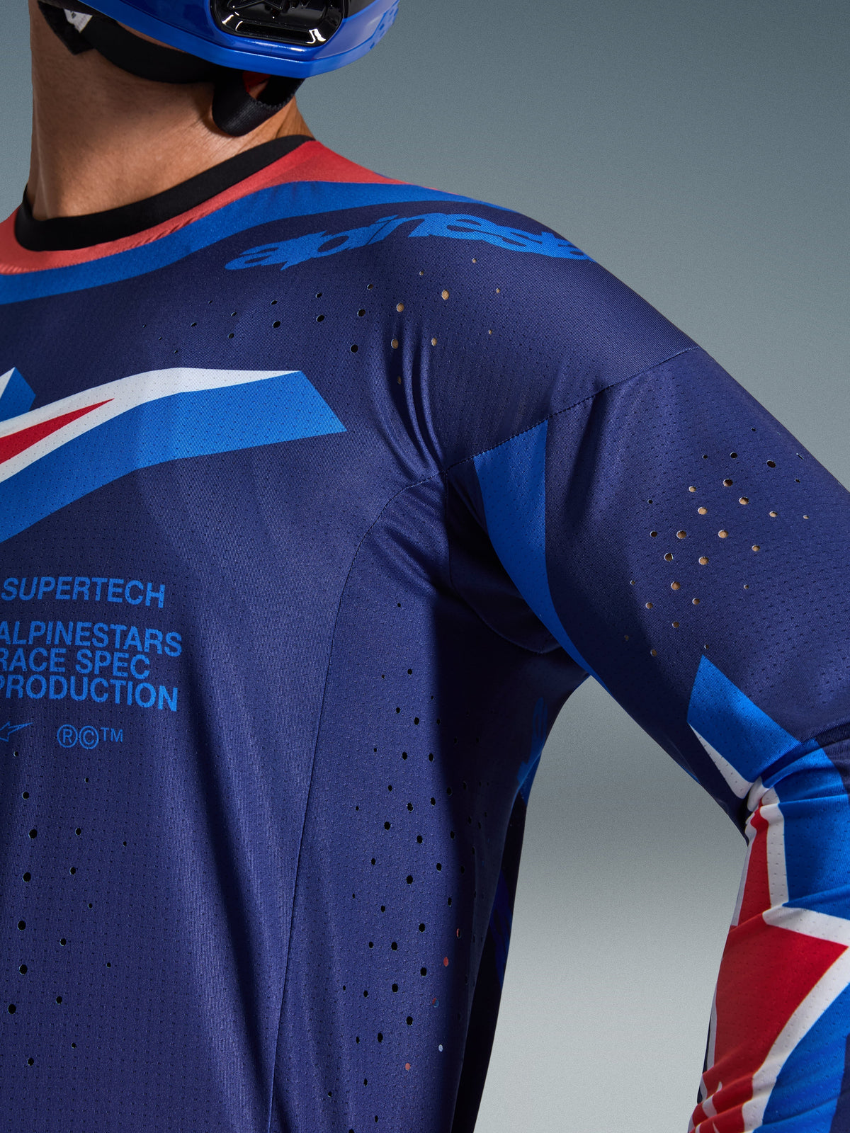 Jersey Alpinestars Supertech Vista 2026, jersey de motocross, azul marino oscuro con detalles en coral intenso y cobalto, primer plano que muestra las perforaciones de ventilación cortadas con láser y la textura de malla transpirable, incluye la marca 'Supertech Race Spec', equipamiento de competición de nivel profesional