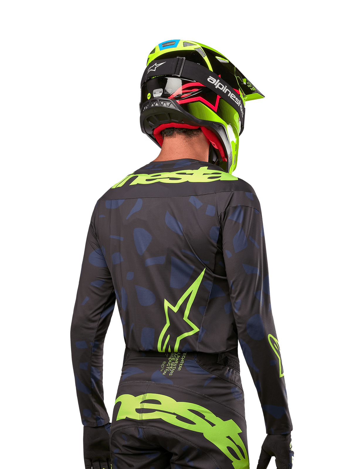 Vista trasera de un piloto de motocross con el Jersey Alpinestars 2024 Techstar Rantera en negro navy y amarillo flúor, con logotipos destacados en la espalda, combinado con pantalones a juego y un casco amarillo neón para un look de competición off-road completo.