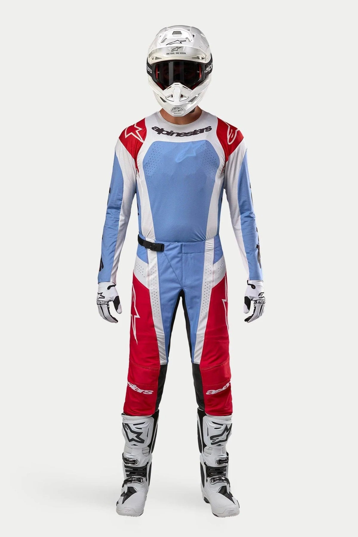 Piloto de motocross con Jersey Techstar Ocuri 2024 en azul claro, rojo Marte y blanco, pantalones de motocross a juego, casco blanco con gafas y botas blancas, conjunto de equipamiento profesional completo para carreras fuera de carretera