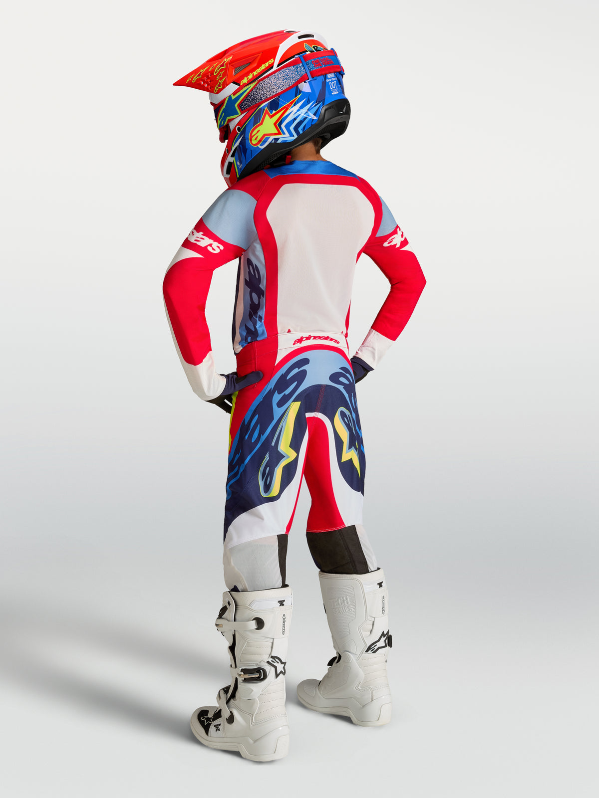 Alpinestars Supertech Dyna juvenil, conjunto de motocross rojo fuego y azul marino, ajuste de carrera, vista trasera.