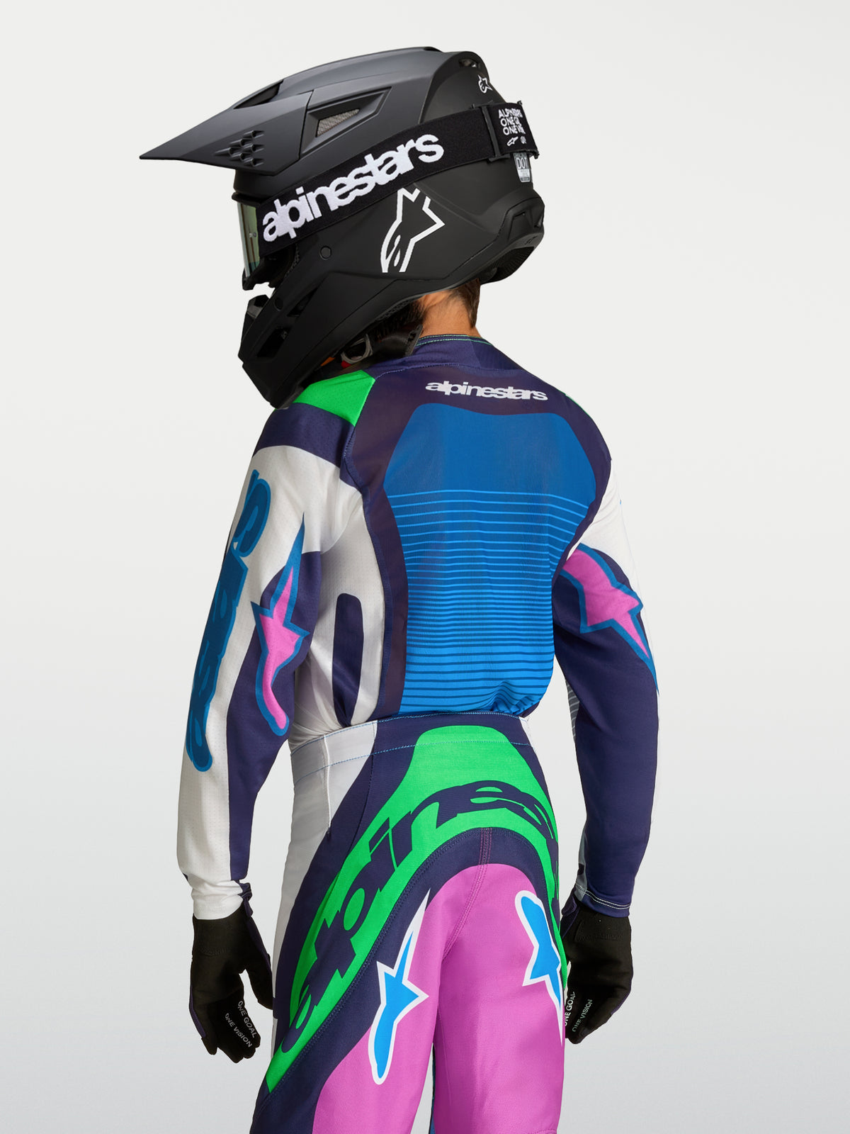 Jersey Supertech Maven Juvenil de Alpinestars, equipo de motocross azul y verde para jóvenes, vista trasera con casco.