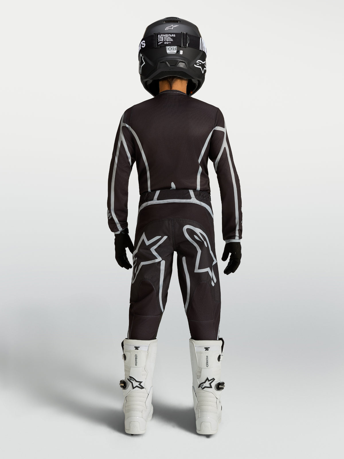 Alpinestars Youth Fluid Apex V2 Jersey and Gear Set, black and silver motocross kit with white boots, rear view.