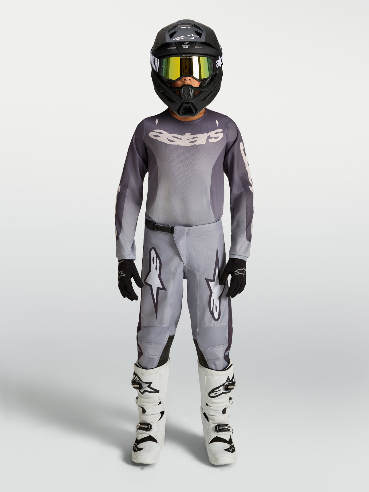 Alpinestars 2027 Youth Fluid Amber Jersey and Gear Set, gray and sand motocross outfit with black helmet and white boots.