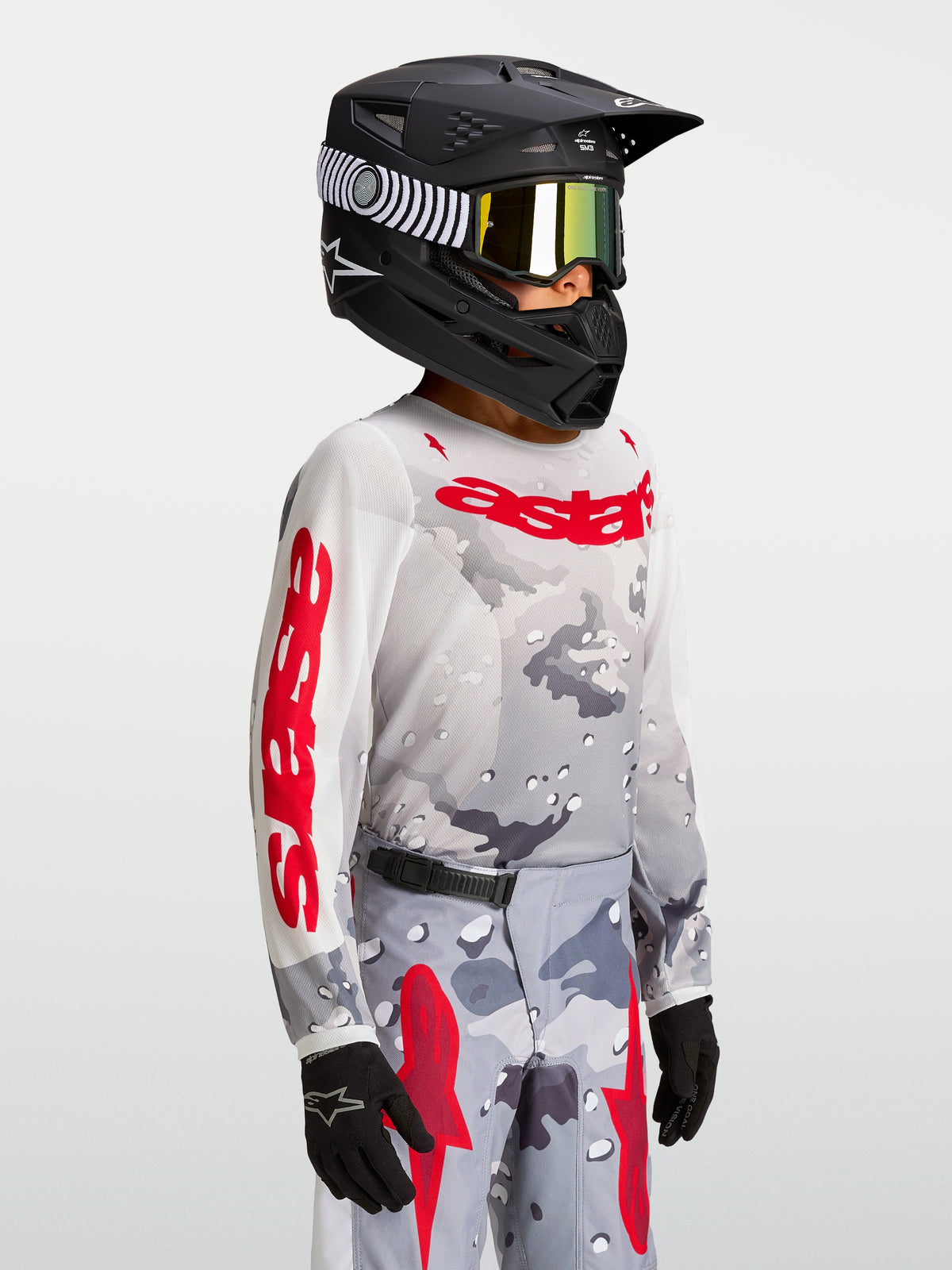 Alpinestars Jersey Fluid Lone Juvenil 2027, jersey de motocross para off-road, juvenil, gris camuflaje y rojo fuego, confección en poliéster ligero y transpirable, usado en modelo con casco y guantes