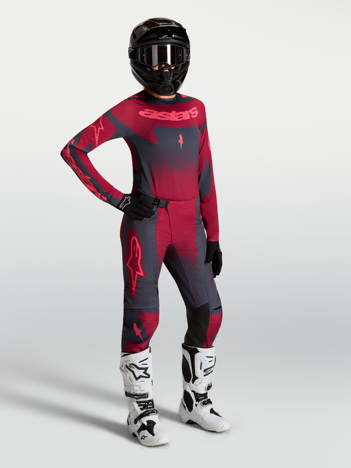 Alpinestars Stella Techstar Swan, equipación de motocross para mujer en carmesí y gris oscuro con botas blancas.
