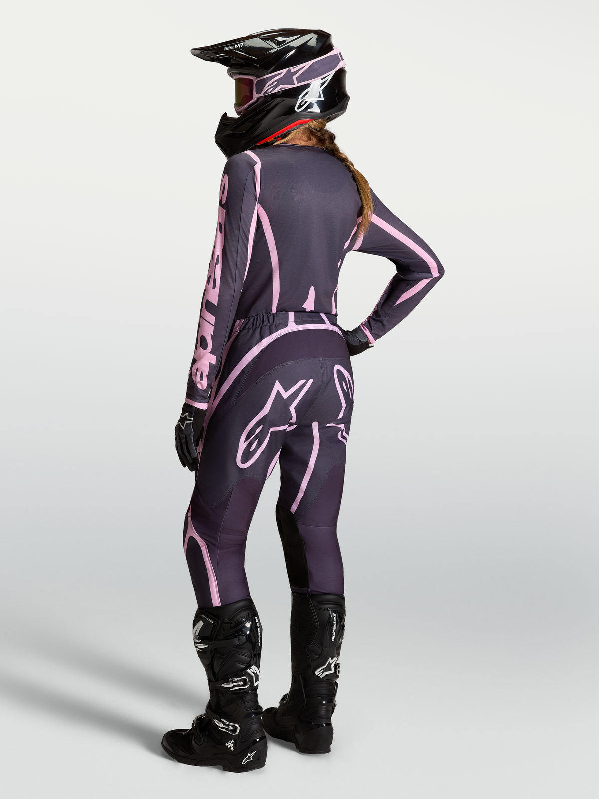 Alpinestars Stella Fluid Apex V2 jersey y conjunto de motocross para mujer, gris y rosa, con casco y botas negras.