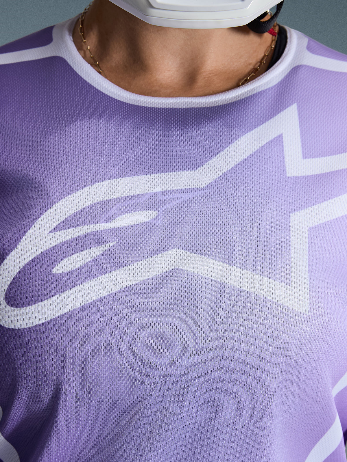Alpinestars 2026 Stella Fluid Apex Jersey, primer plano del pecho, morado con gráficos blancos, con un gran logotipo de Astars blanco sobre construcción de tejido de malla poly-fabric