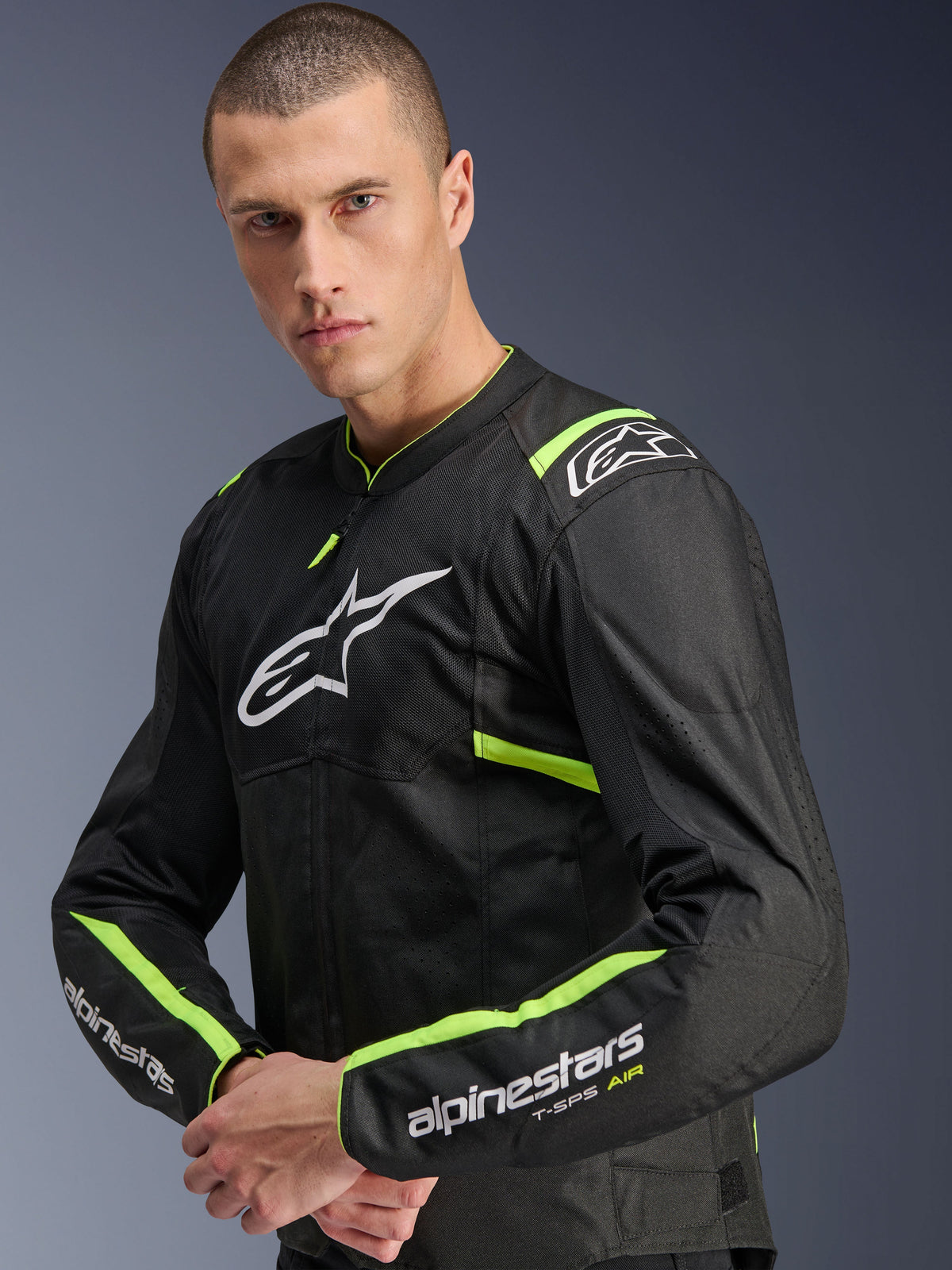 Chaqueta Alpinestars T-Sps Air V2, Negro Amarillo Fluo, chaqueta textil de moto usada por un modelo, con paneles de malla técnica para el flujo de aire, logo blanco de Alpinestars en el pecho y detalles en amarillo flúor en hombros y mangas.