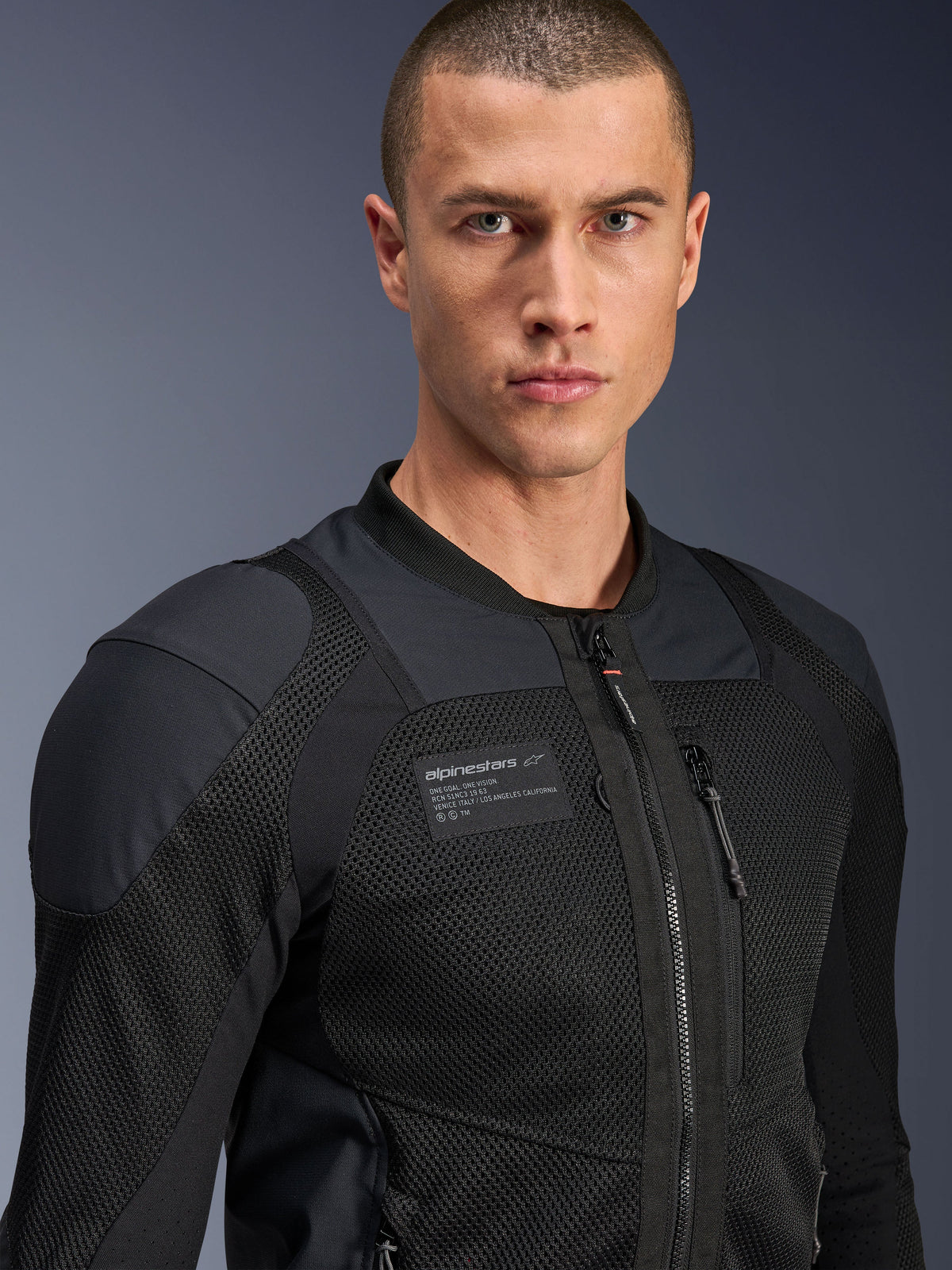 Chaqueta Alpinestars Troop-Air Pro, negra, chaqueta de aire técnica blindada para motociclismo, primer plano que muestra la textura de malla 2D y el parche de la marca en el pecho.