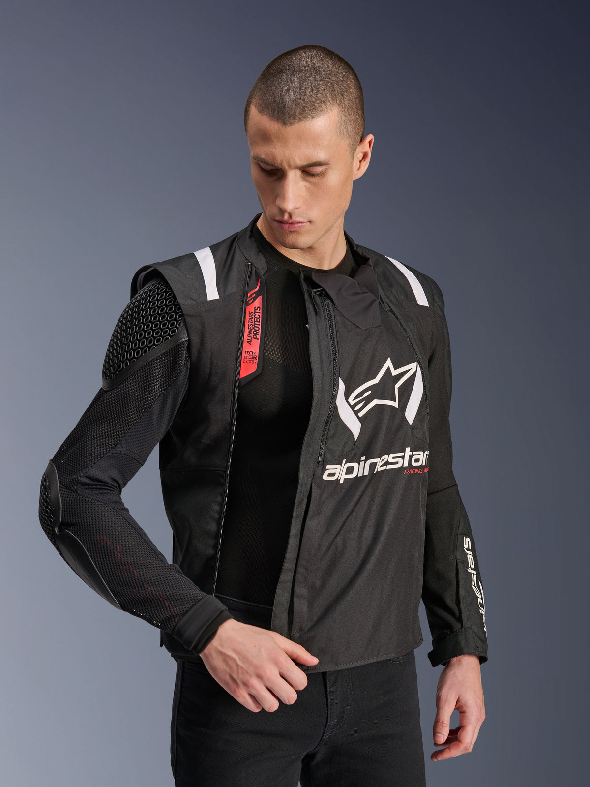 Alpinestars T-Stunt Air Jacket, Black and White motorcycle jacket, worn by male model, showcasing modular mesh construction and exposed internal armor on shoulder and elbow, Alpinestars branding on chest, Tech-Air Ready feature, sports-cut for road riding