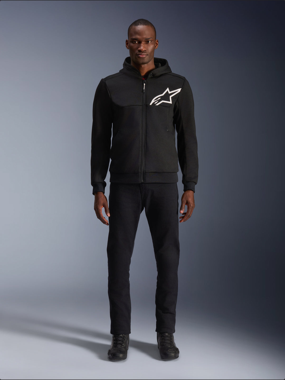 Sudadera Alpinestars Chrome V2 Sport, chaqueta de moto urbana negra con logo blanco y forro polar, vestida por un modelo.