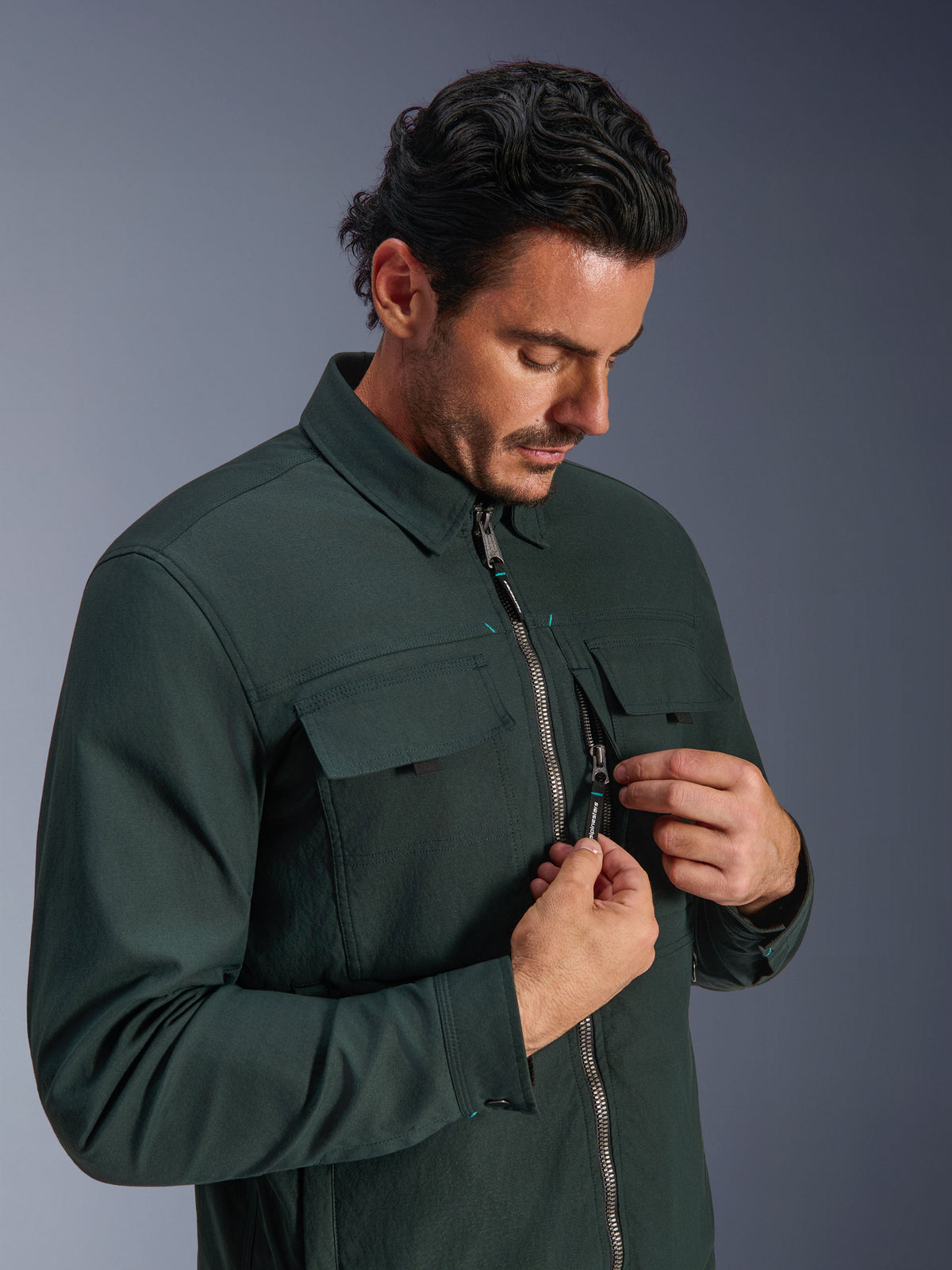 Alpinestars Bryon WR Overshirt in Dark Emerald, urban motorcycle jacket, worn by a man demonstrating the vertical zippered chest pocket and cargo pockets, featuring a durable waxed canvas texture and workwear-inspired design.