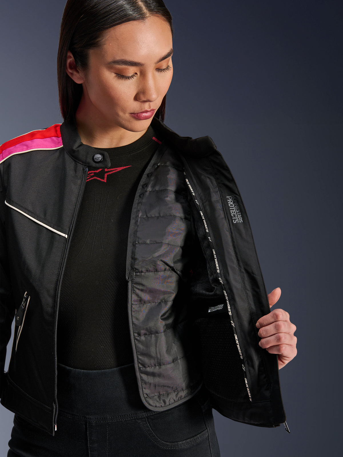 Chaqueta Alpinestars Stella T-Dyno WR, chaqueta de moto textil en negro, rojo brillante y fucsia, abierta para mostrar el chaleco térmico acolchado interno y el bolsillo impermeable, ajuste de motociclista de inspiración vintage para mujer