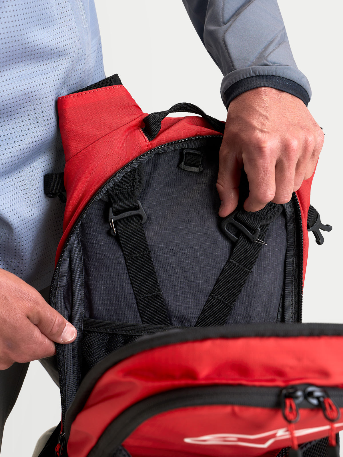Alpinestars Mochila AT-9, mochila de motocross, negra y rojo brillante, vista en primer plano de los compartimentos de almacenamiento interiores y las correas de ajuste del arnés