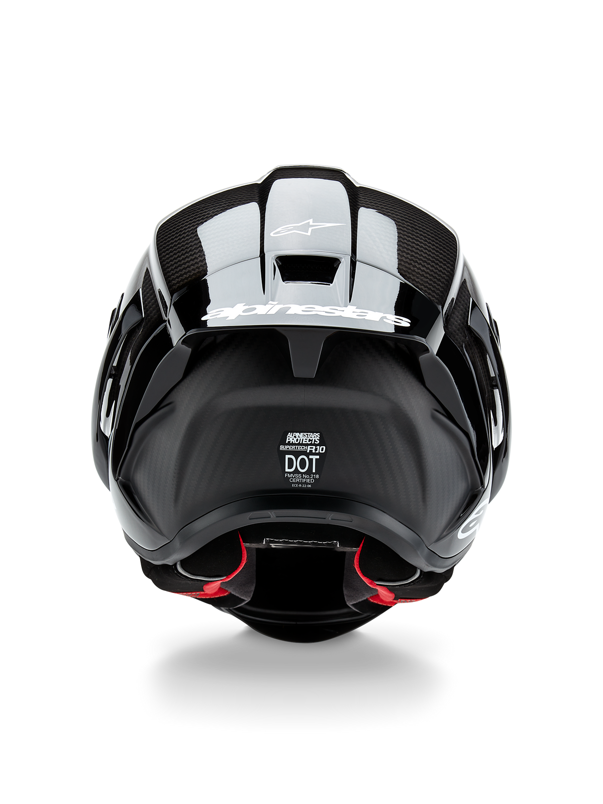 Casco Alpinestars Supertech R10 Solid, casco de moto, carbono negro mate y brillante, vista trasera con textura de fibra de carbono, alerón aerodinámico con logotipo blanco de Alpinestars, etiquetas de certificación de seguridad DOT y ECE, y acolchado interior rojo