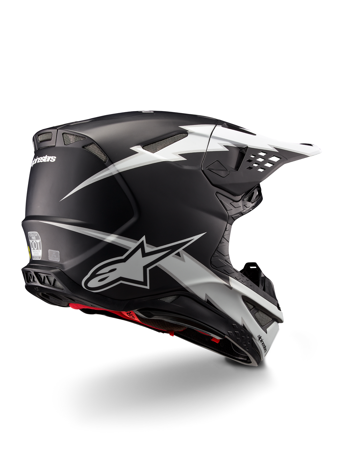 Casco Alpinestars Supertech M10 Ampress, casco de motocross, negro y blanco mate, con llamativos gráficos de rayos blancos sobre una calota negra mate, vista trasera de tres cuartos que muestra el logotipo de Alpinestars y los puertos de ventilación