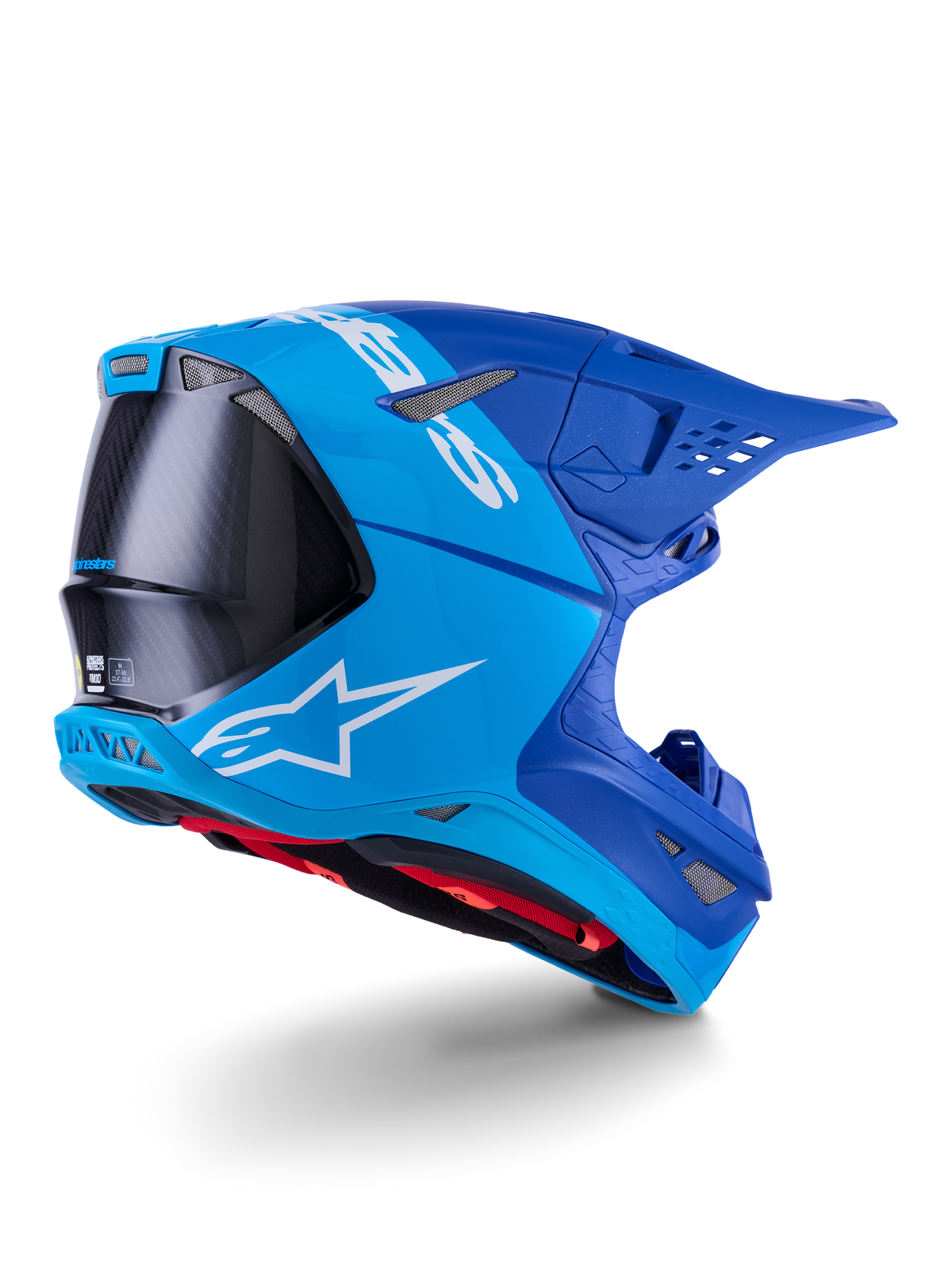 Casco Alpinestars Supertech M10 Flood, casco de motocross, azul brillante y azul marino con fibra de carbono negra expuesta, perfil lateral trasero que muestra los puertos de ventilación y el logotipo blanco, forro interior rojo, diseño aerodinámico avanzado para rendimiento off-road