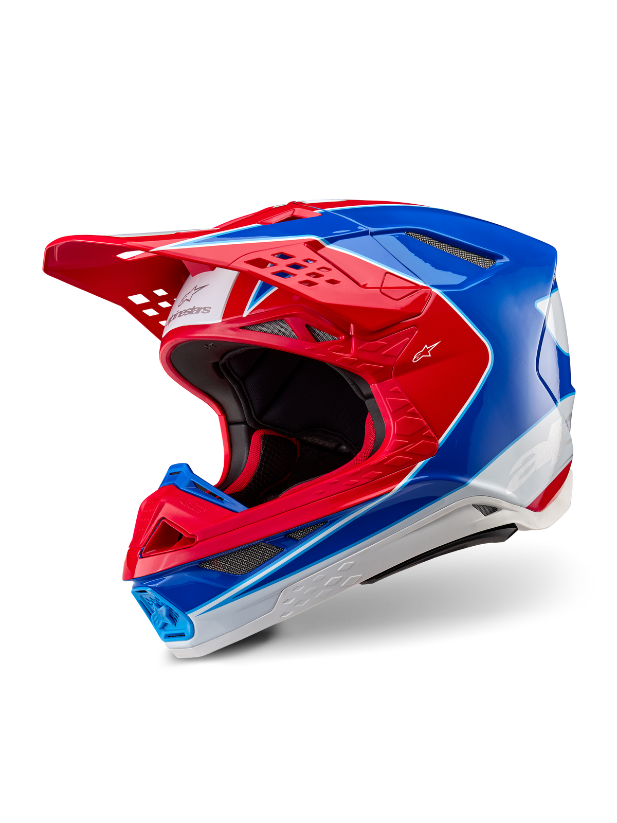 Casco Alpinestars Supertech M10 Aeon, casco de motocross, rojo y azul brillante, vista de tres cuartos que muestra la carcasa aerodinámica con múltiples puertos de ventilación, detalles gráficos en blanco y rojo, logotipo de Alpinestars en la visera y el lateral, equipo profesional de carreras todoterreno