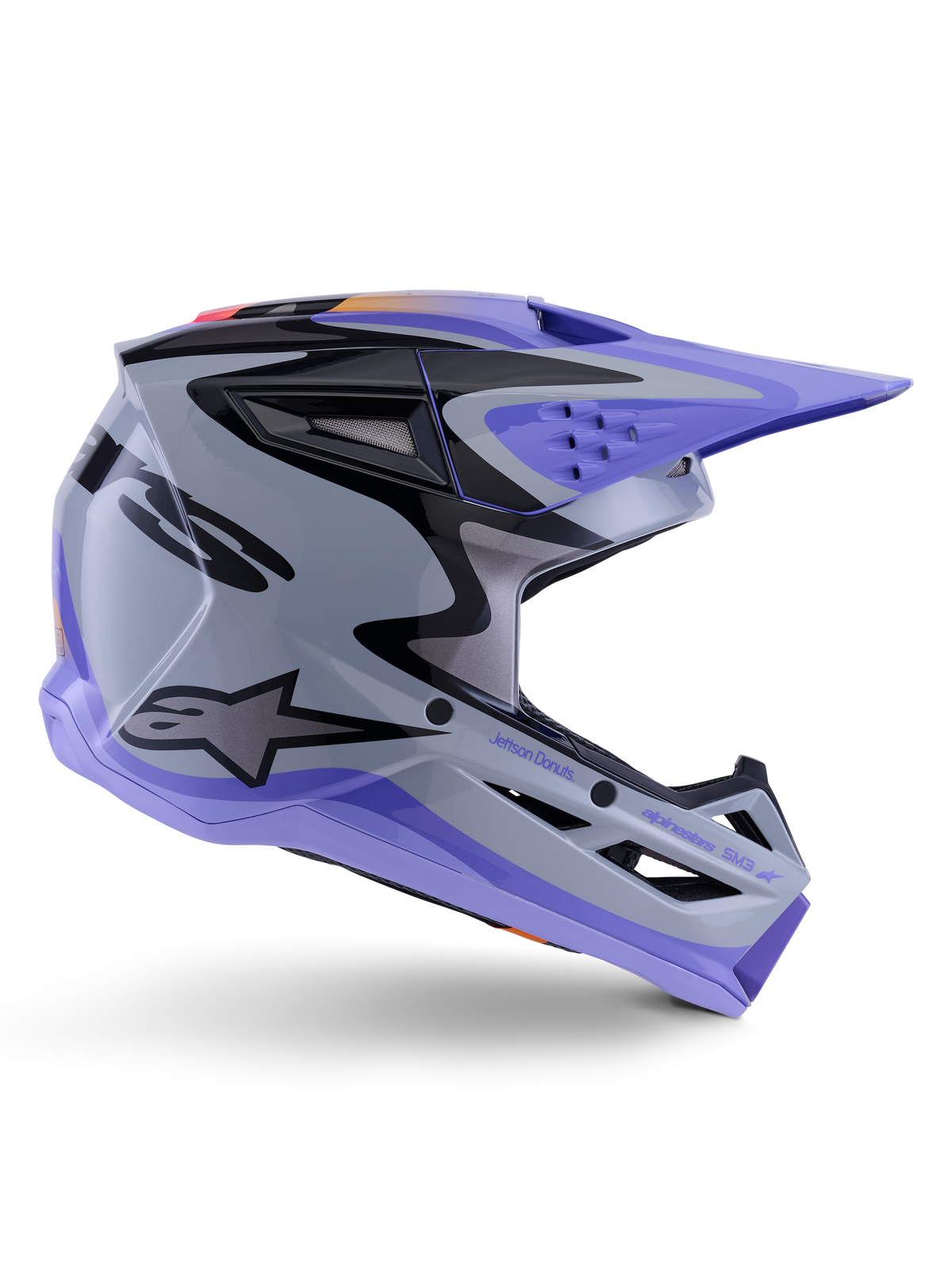 Casco Alpinestars S-M3 Jettson ECE 22.06, casco de motocross, gris, púrpura y negro brillante, vista de perfil lateral con visera y mentonera púrpuras, carcasa aerodinámica con gráficos negros, múltiples puertos de ventilación y marca "Jettson Donuts" en el lateral.