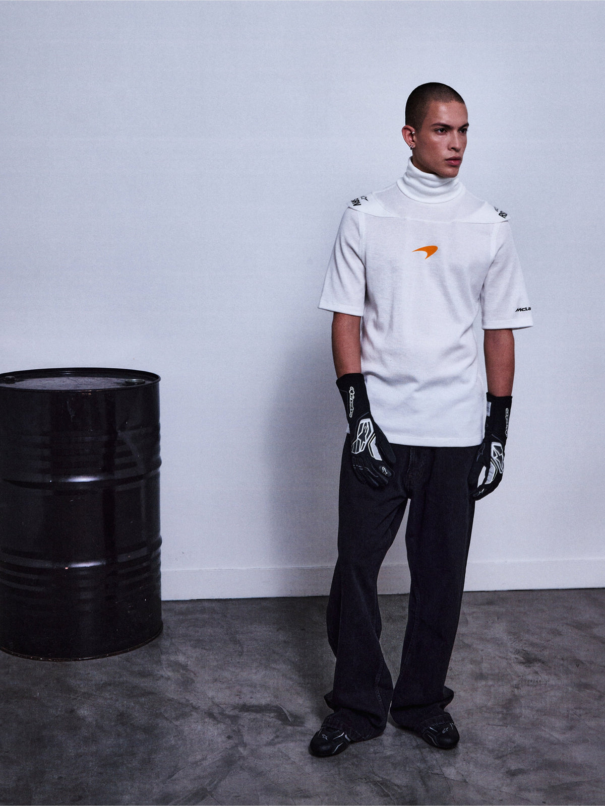 Alpinestars RSRV Pyro SS Tee, camiseta de cuello alto blanca con mangas cortas, logo naranja, estilo urbano premium, persona con guantes negros y pantalones negros