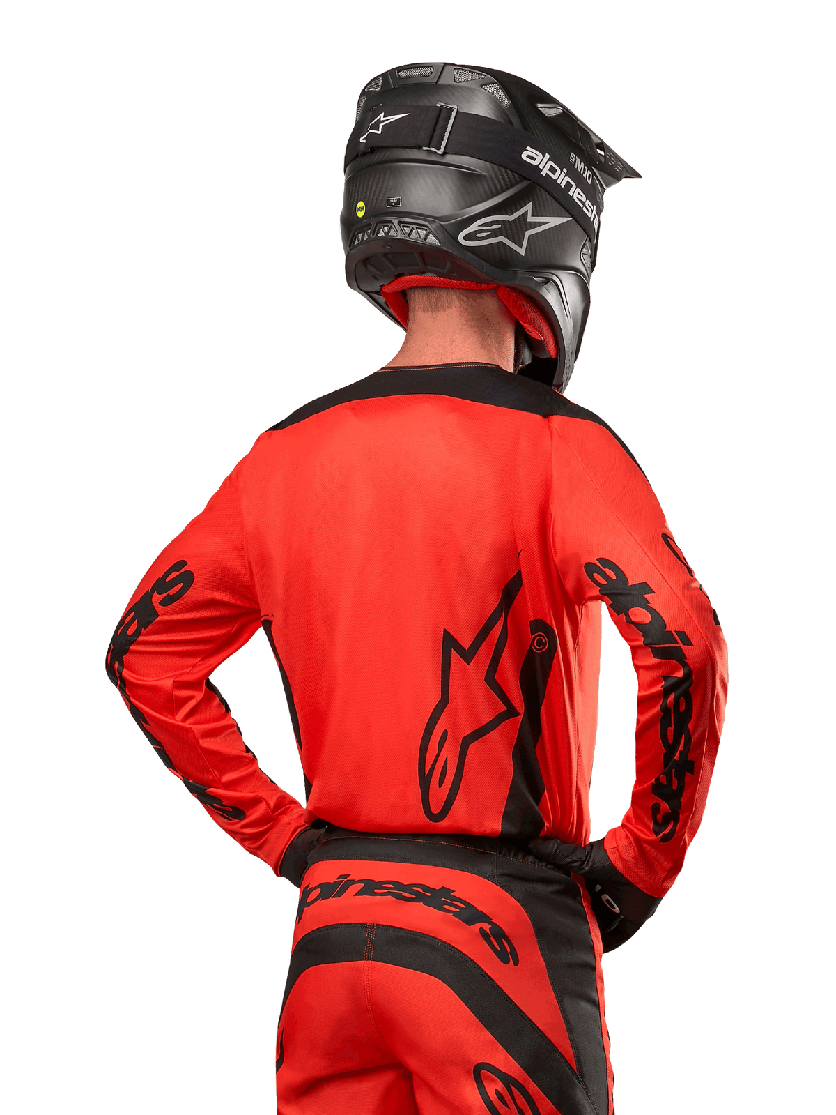Piloto de motocross desde atrás con el jersey Alpinestars 2024 Fluid Lurv en naranja intenso y negro, con el logotipo de Alpinestars destacado en la espalda y las mangas, combinado con pantalones de motocross a juego y casco negro, diseñado para rendimiento en carreras todoterreno.