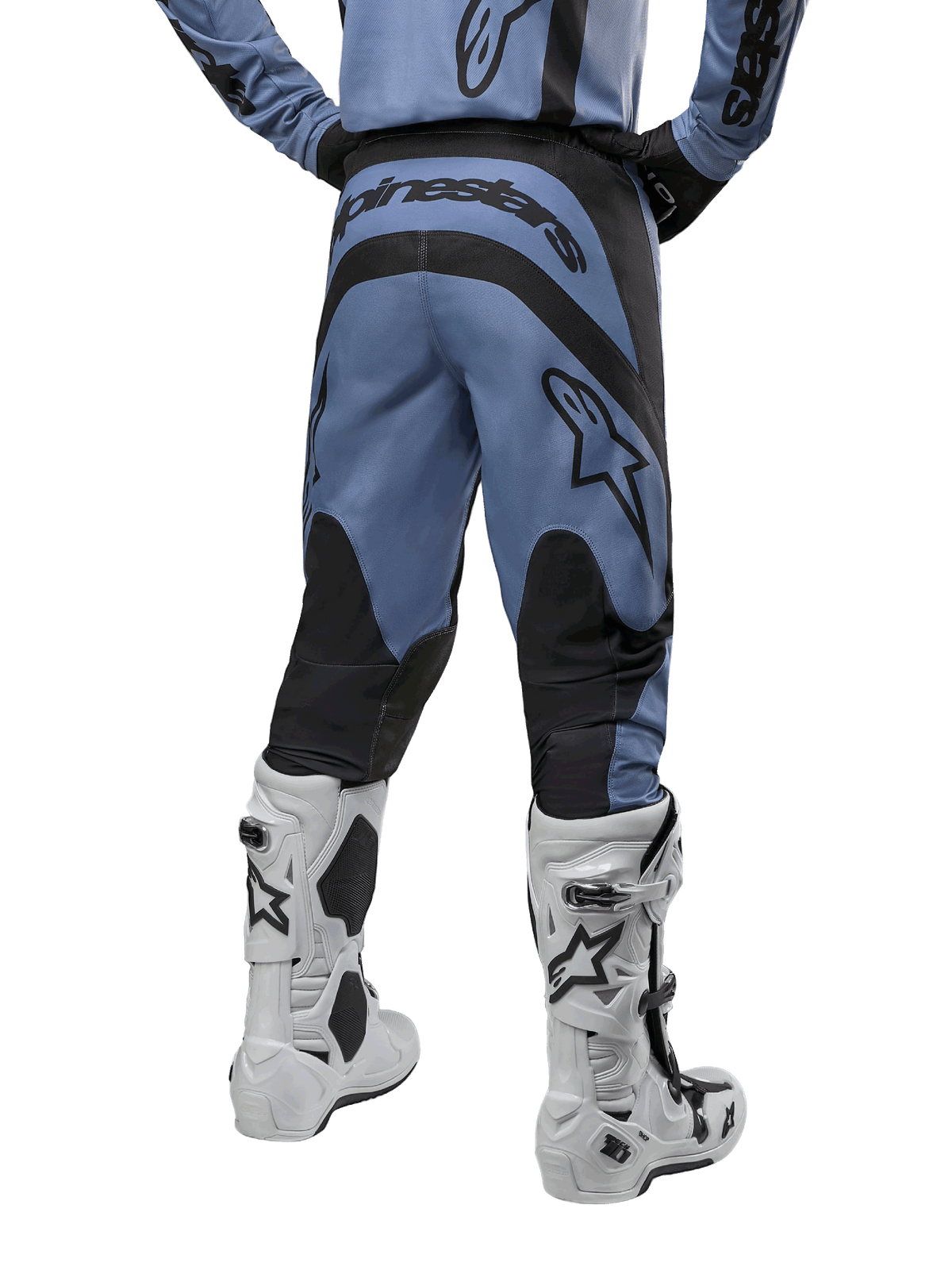 Pantalones Alpinestars Fluid Lurv 2024, pantalones de motocross, azul claro y negro, vista trasera que muestra paneles reforzados negros y logotipo grande de la marca, combinados con botas de motocross blancas y negras, equipamiento de carreras profesional para conducción off-road
