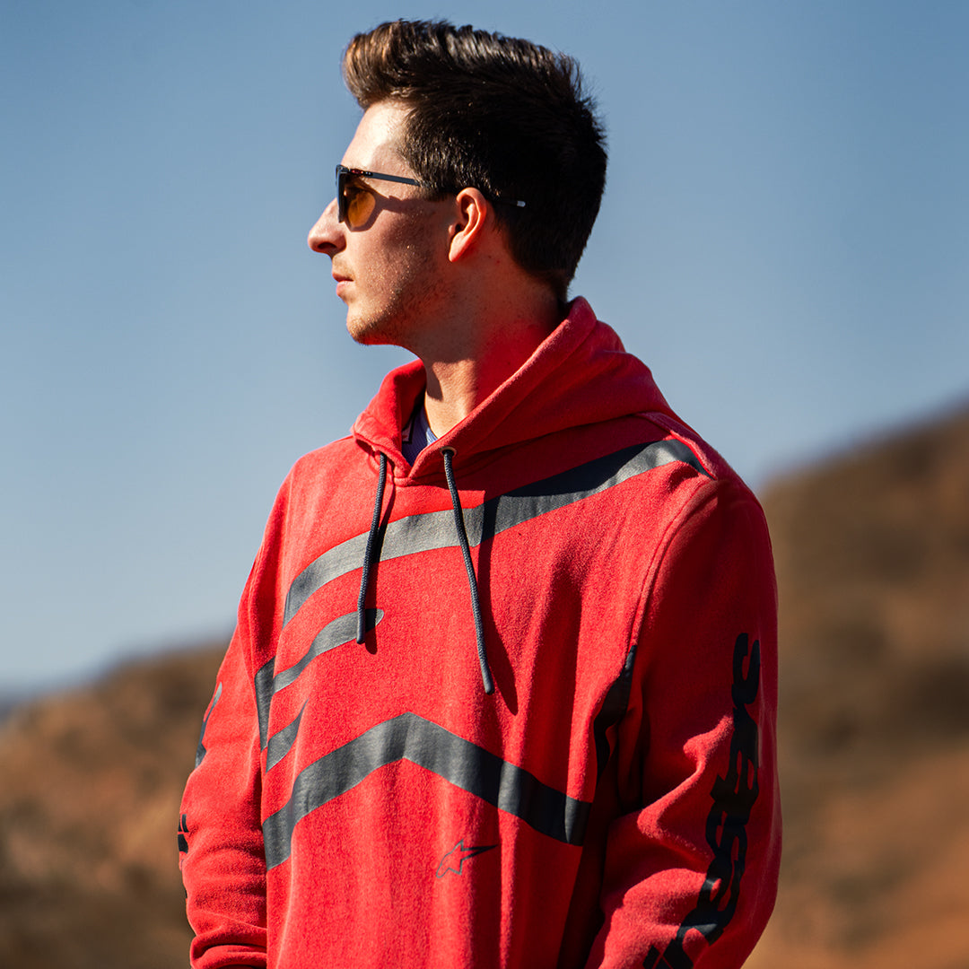 Alpinestars Unbound Hoodie, sudadera de forro polar roja teñida en prenda, con logotipo negro extragrande en el pecho y marca Alpinestars en las mangas, capucha con cordón, estilo urbano casual inspirado en el automovilismo