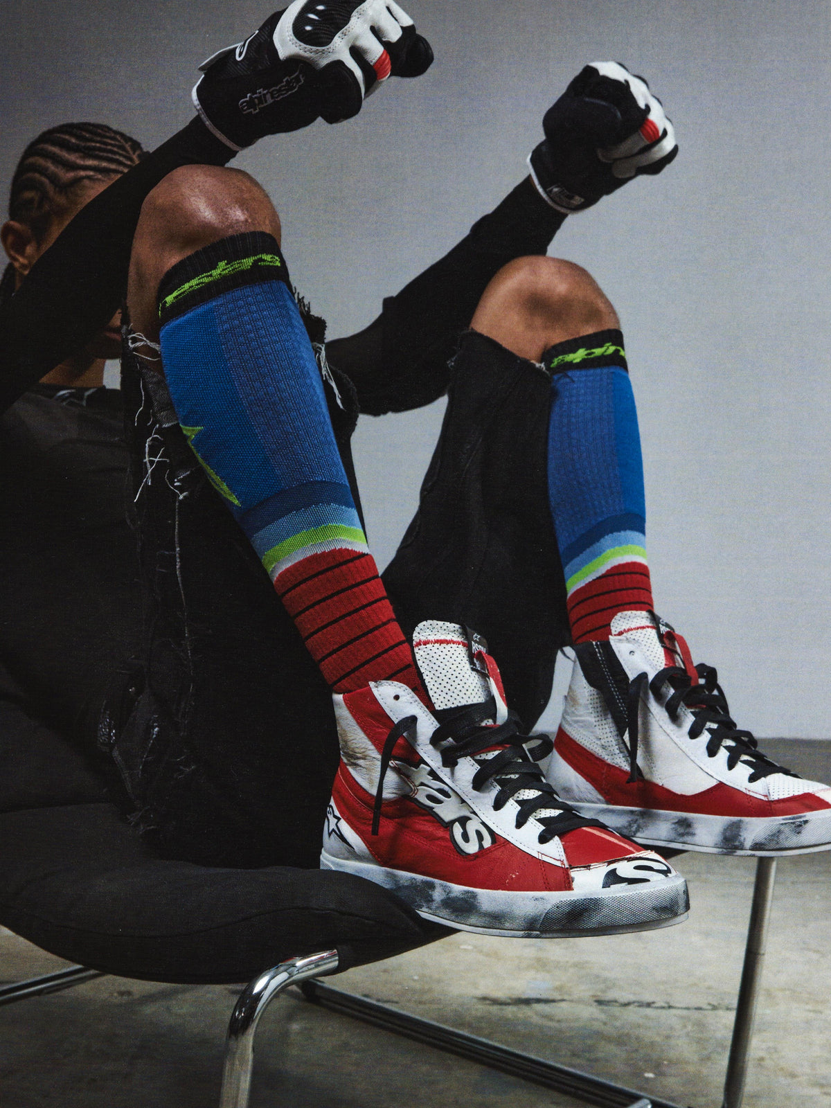 Alpinestars RSRV Legacy Shoe, zapatillas altas rojas, blancas y negras con cordones negros, estilo urbano premium, persona sentada con calcetines coloridos a rayas