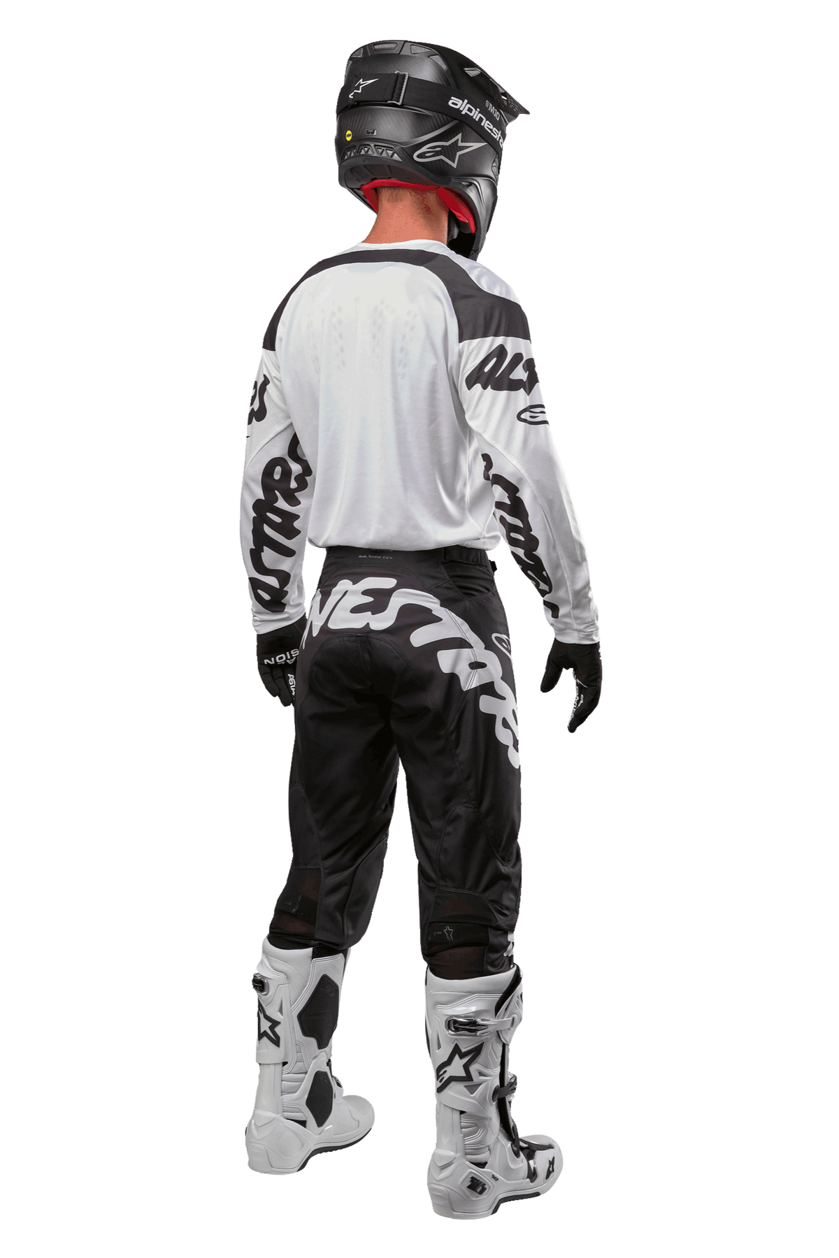 Alpinestars 2024 Racer Hana Pants, pantalones de motocross negros y blancos, vista trasera mostrando el diseño con logo Alpinestars, equipamiento completo con jersey blanco, casco negro y botas blancas protectoras