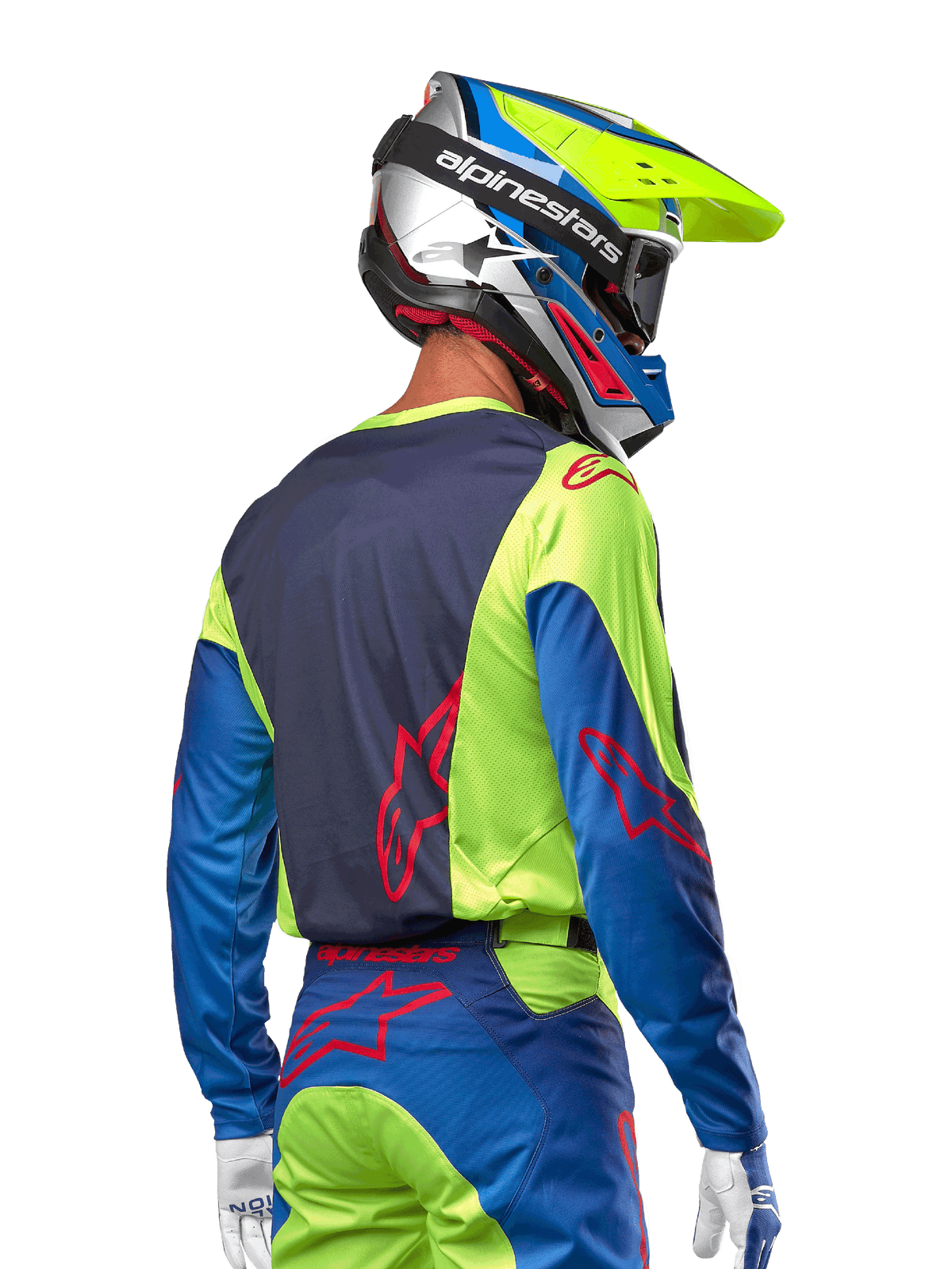 Piloto de motocross vistiendo el jersey Alpinestars 2024 Racer Hoen en amarillo flúor y azul marino, con un logotipo de estrella roja en la espalda, pantalones de motocross a juego y casco de carreras coordinado, vista trasera que muestra el diseño ergonómico para rendimiento todoterreno.