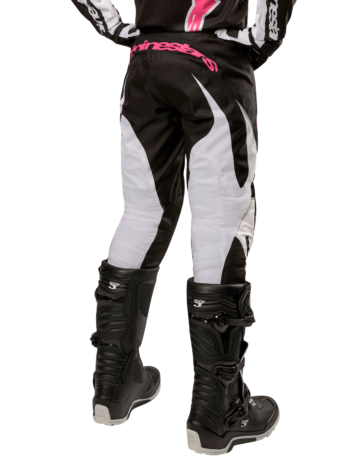 Alpinestars Stella Fluid 2024 para mujer, pantalones de motocross en negro y blanco, vista trasera con paneles blancos en las piernas y logotipo rosa en la cintura, combinados con botas Tech 3 negras, equipamiento duradero para competiciones off-road