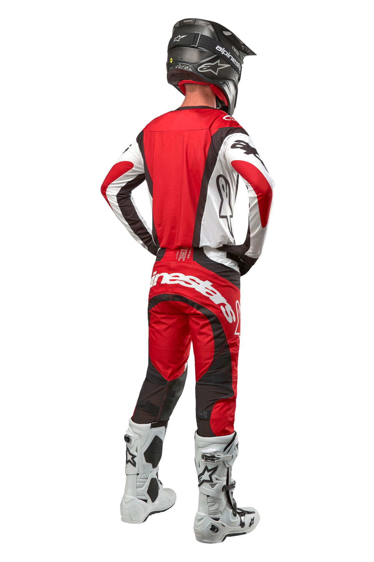 Alpinestars 2024 Techstar Ocuri Pants, Motocross Pants, Mars Red White Black, rear view of a motocross rider wearing full racing gear, including matching jersey, black helmet, and white and black boots, highlighting the Alpinestars branding and durable fabric construction.