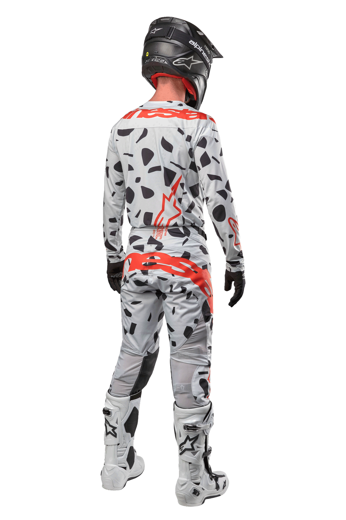 Motocross rider from the back wearing Alpinestars 2024 Techstar Rantera Pants, Haze Gray Camo with black spots and red logos, matching jersey, black helmet, and white boots, complete off-road racing outfit